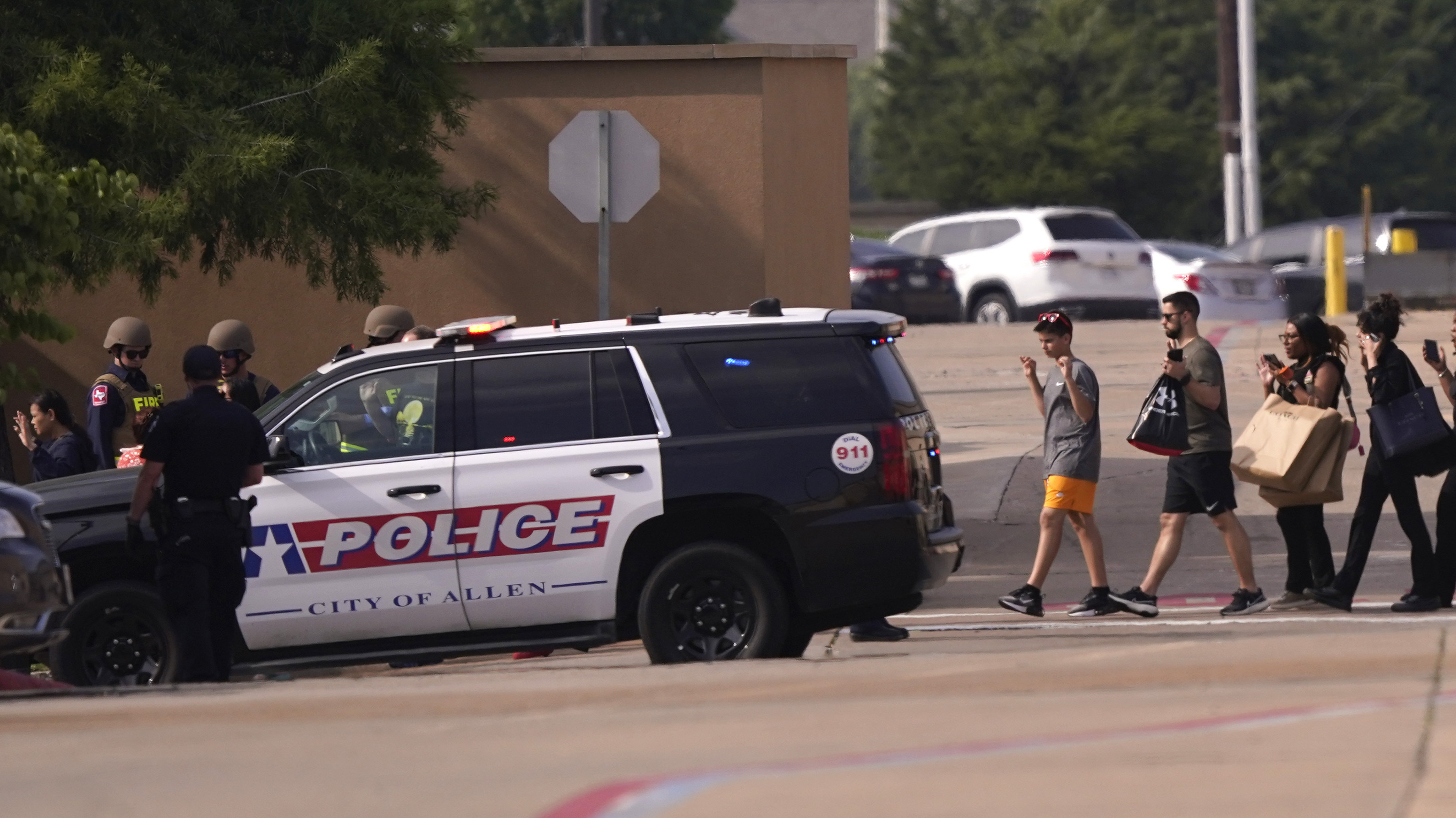 People raise their hands as they leave a shopping center following reports of a shooting, in Allen, Texas, on Saturday.