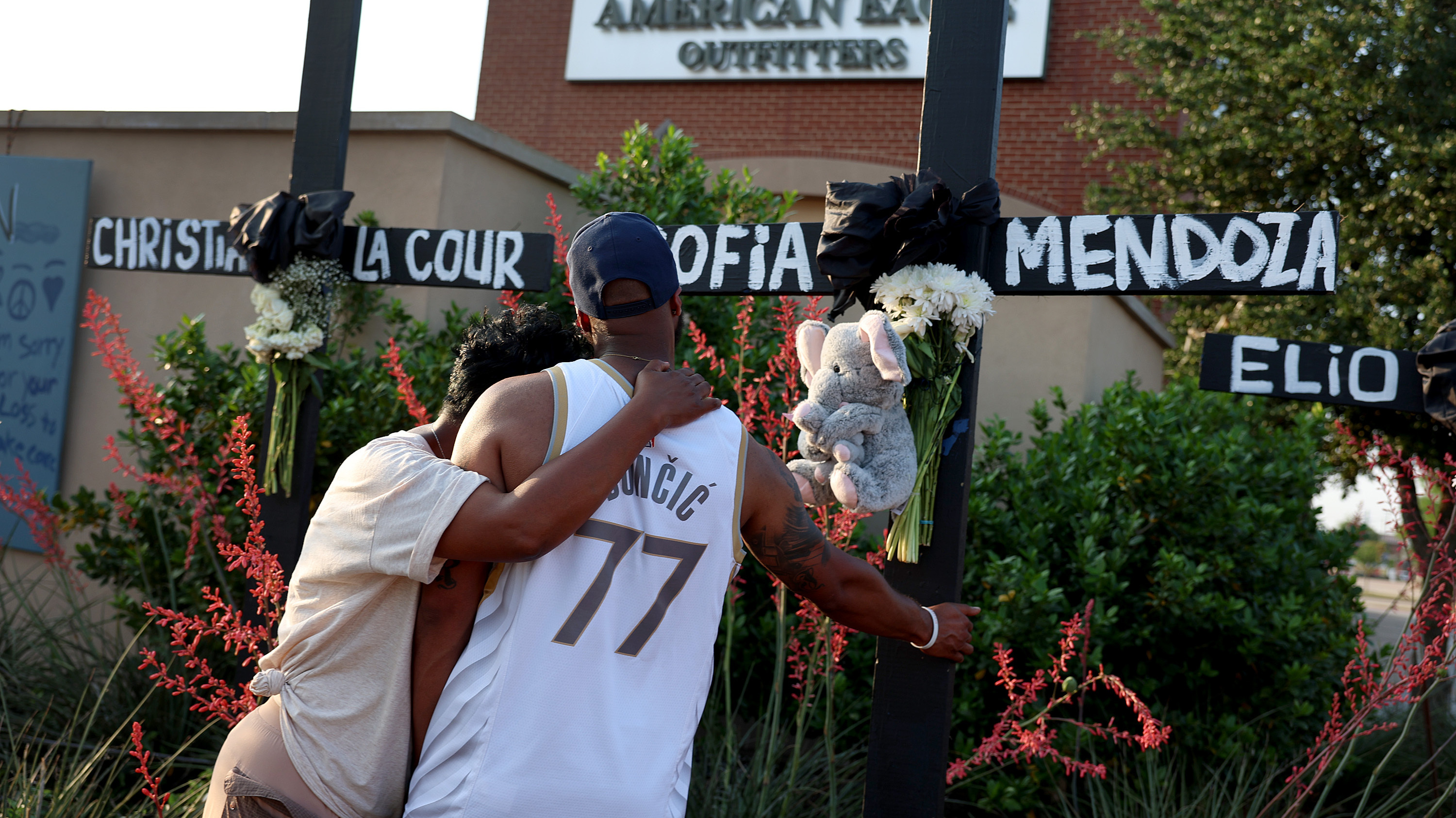Robert Jackson and his mother Cheryl Jackson hug as they visit a memorial near the scene of a mass shooting at the Allen Premium Outlets mall on Monday in Allen, Texas.