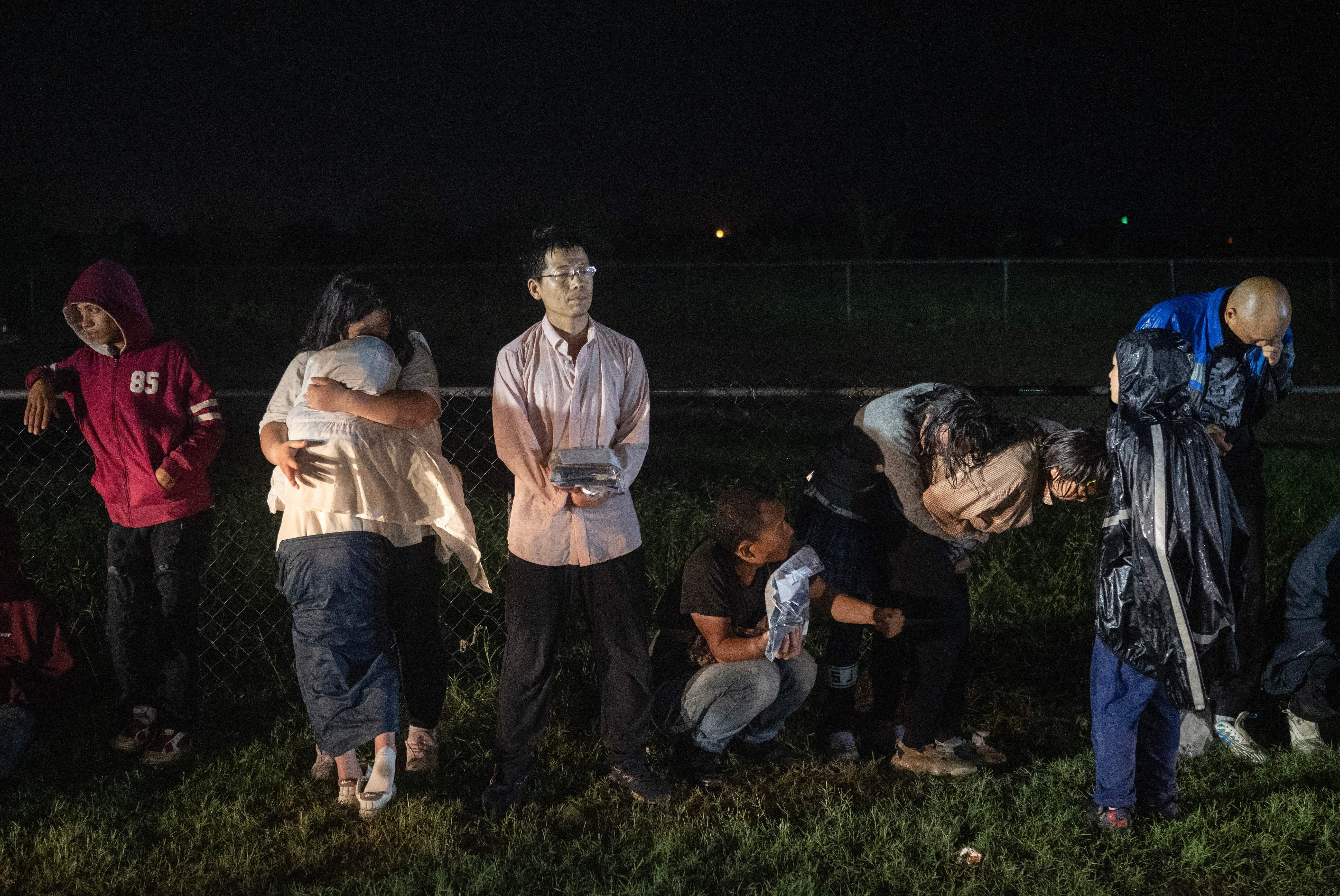 Migrants try to stay warm as they wait in the rain after turning themselves over to U.S. Border Patrol agents after crossing over from Mexico in Fronton, Texas on May 12. (AFP via Getty Images)