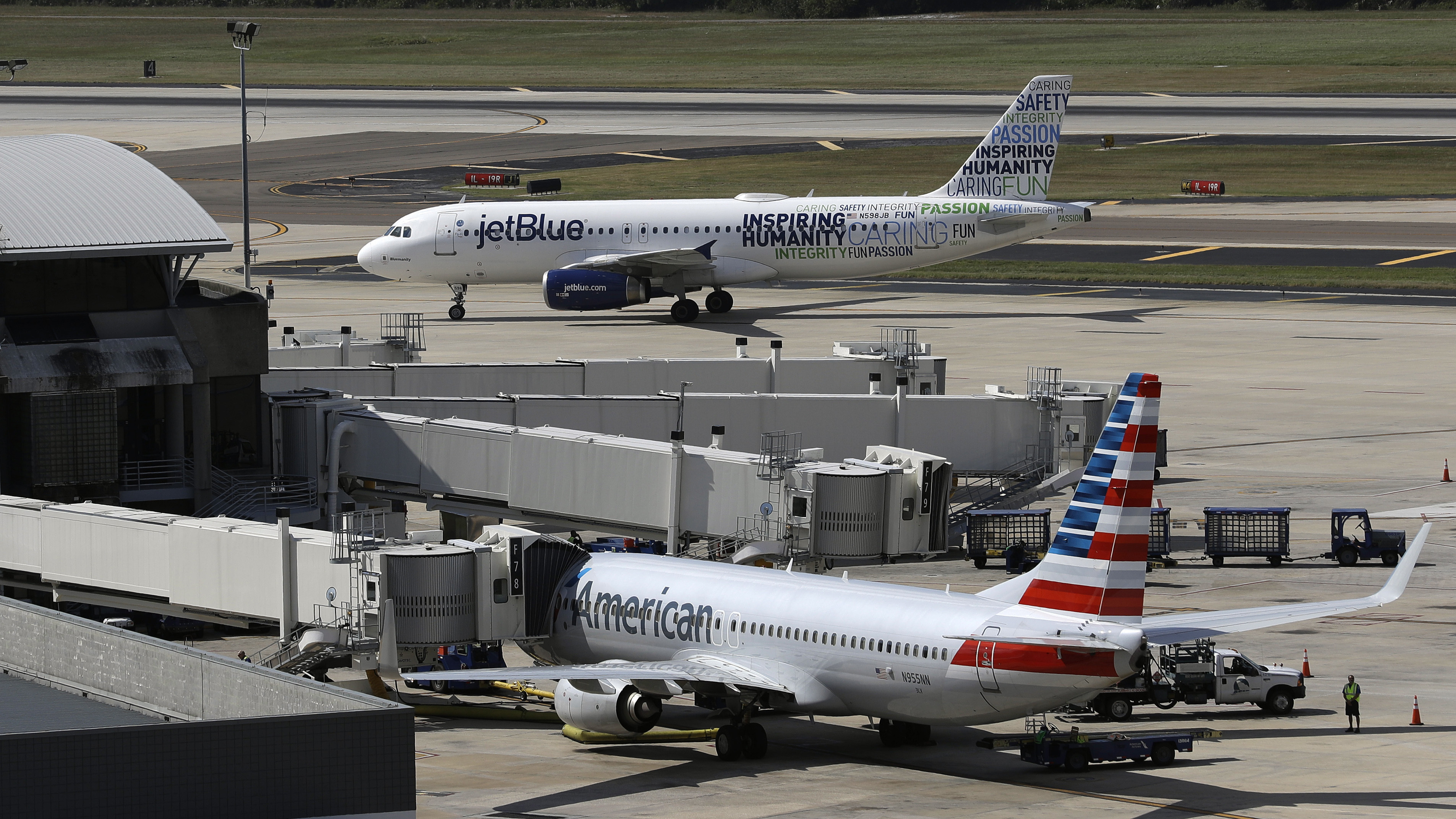 A JetBlue Airbus A320 taxis to a gate on Oct. 26, 2016, after landing, as an American Airlines jet is seen parked at its gate at Tampa International Airport in Tampa, Fla.