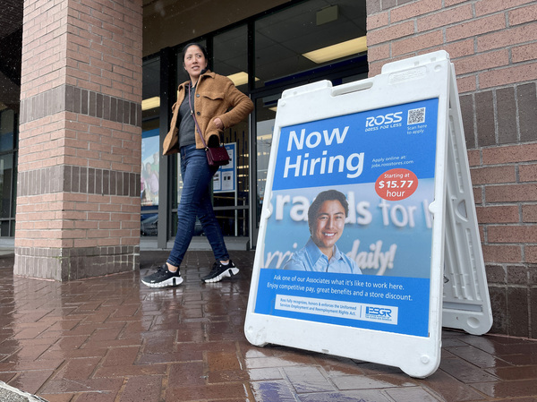 A customer walks by a "Now Hiring" sign posted in front of a store in Novato, Calif., on April 7, 2023. The labor market remains red hot. That's great for workers, but it's bound to reinforce concerns about high inflation.