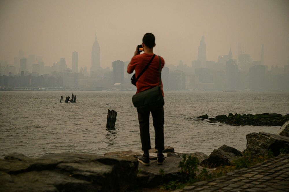 A man stands before the smoky New York City skyline and East River in Brooklyn on Tuesday. (AFP Via Getty Images)