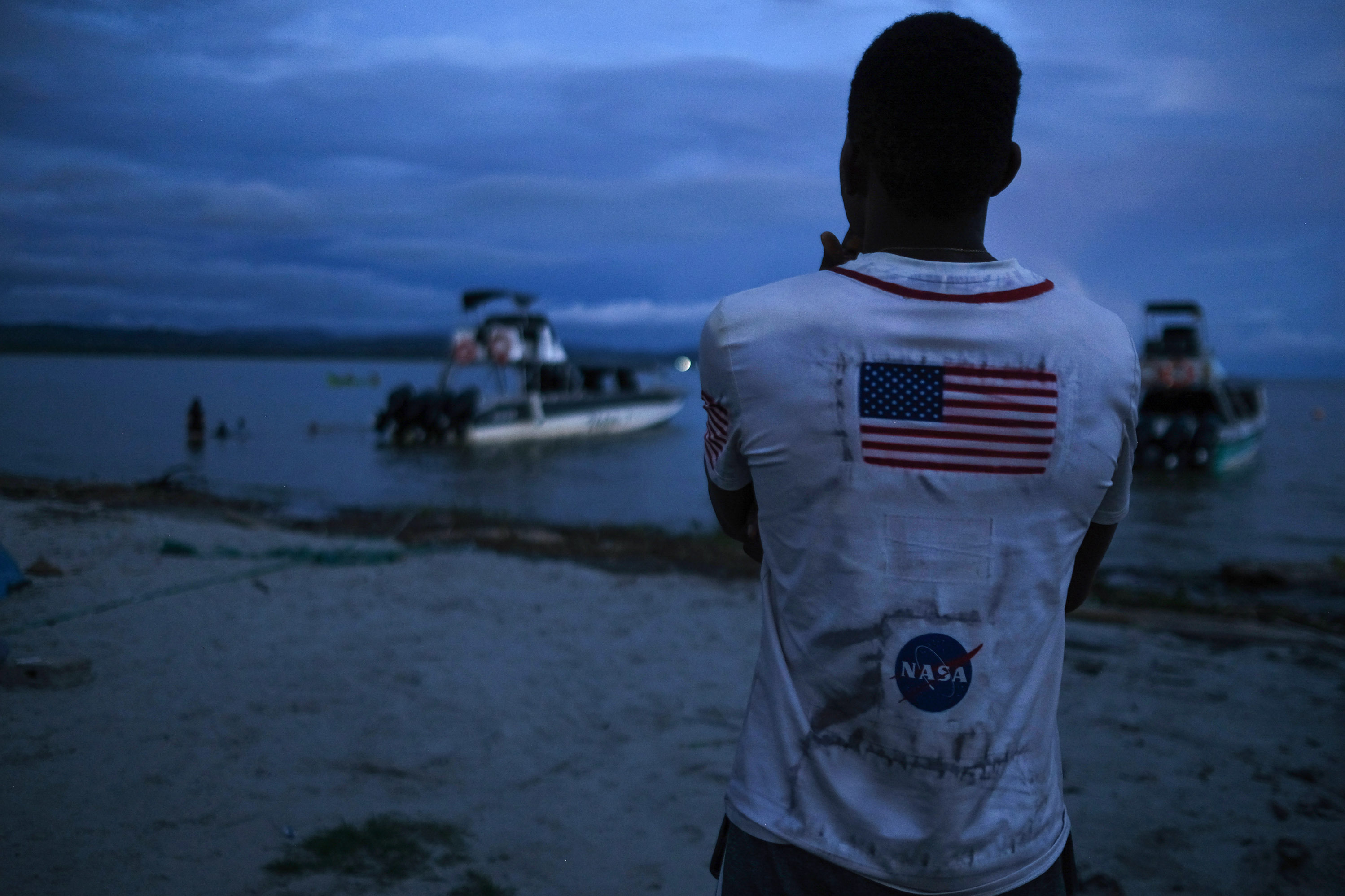 A Venezuelan migrant watches the boat he hopes to take across the Gulf of Urabá once he gets enough money together for the trip. (Carlos Villalon for NPR)