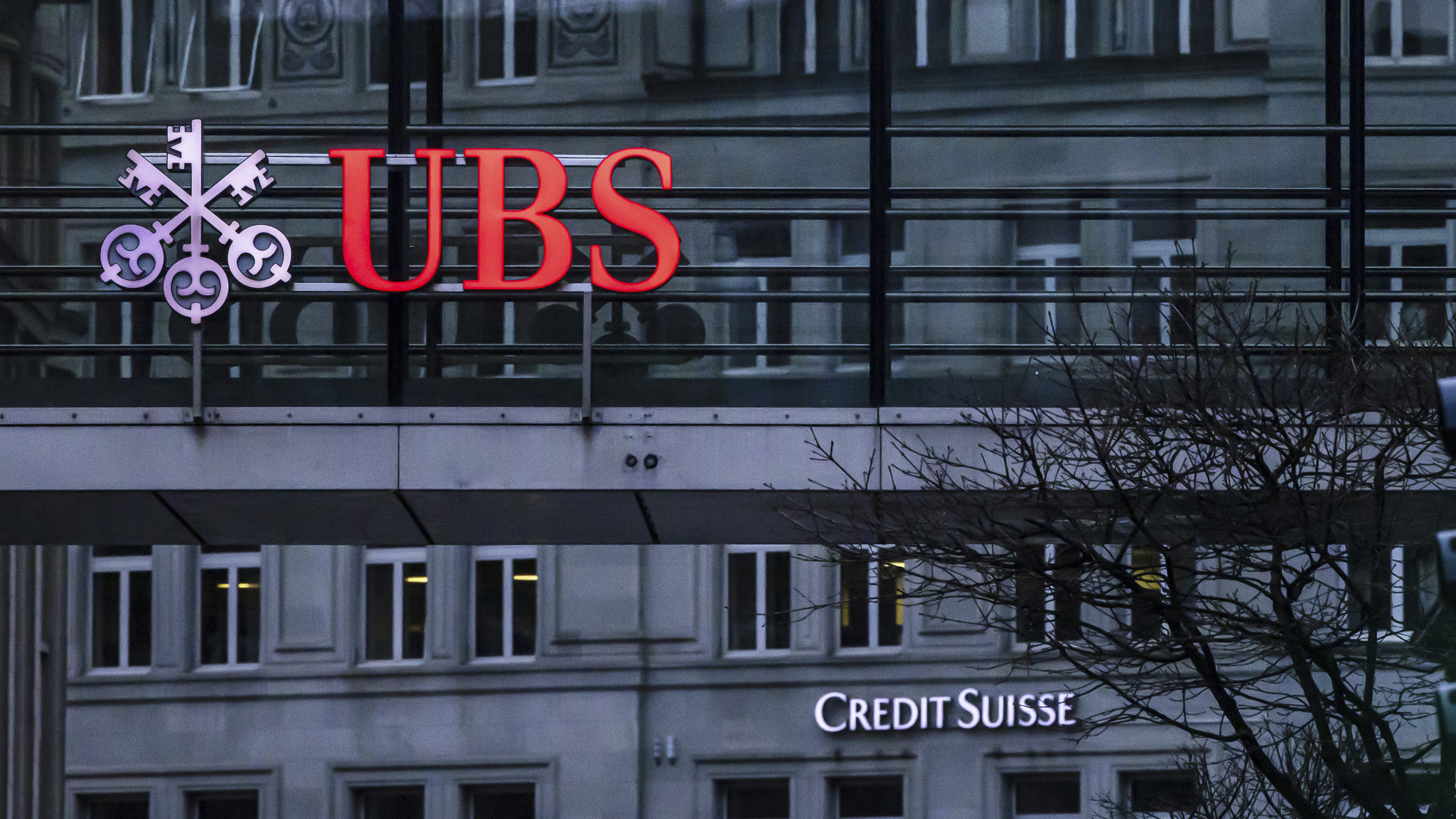 A traffic light signals green in front of the logos of the Swiss banks Credit Suisse and UBS in Zurich, Switzerland, March 19, 2023.