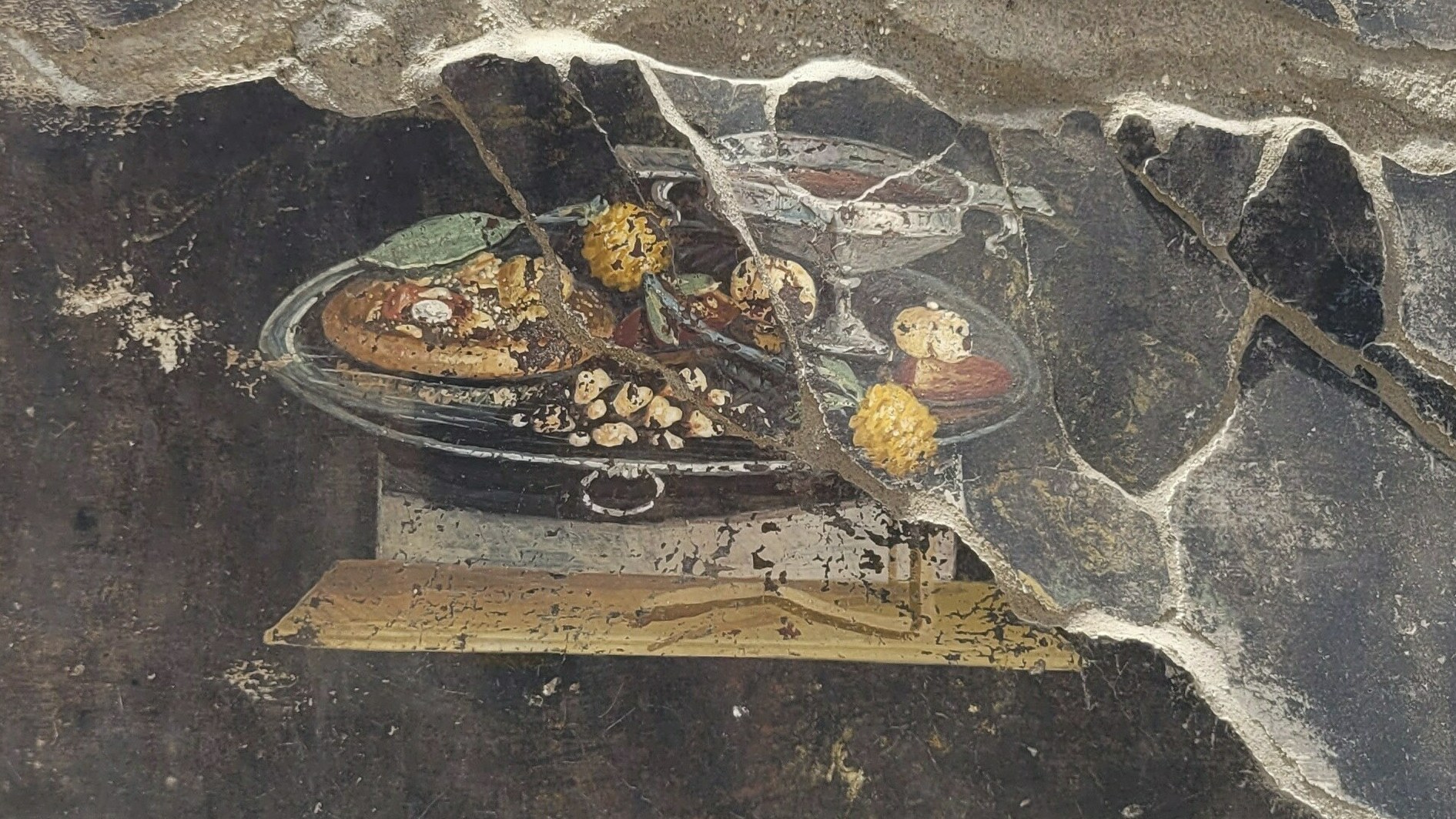 This picture provided on Tuesday, June 27, 2023, by the Pompeii Archaeological Park shows the wall of an ancient Pompeian house with a fresco depicting a table with food.