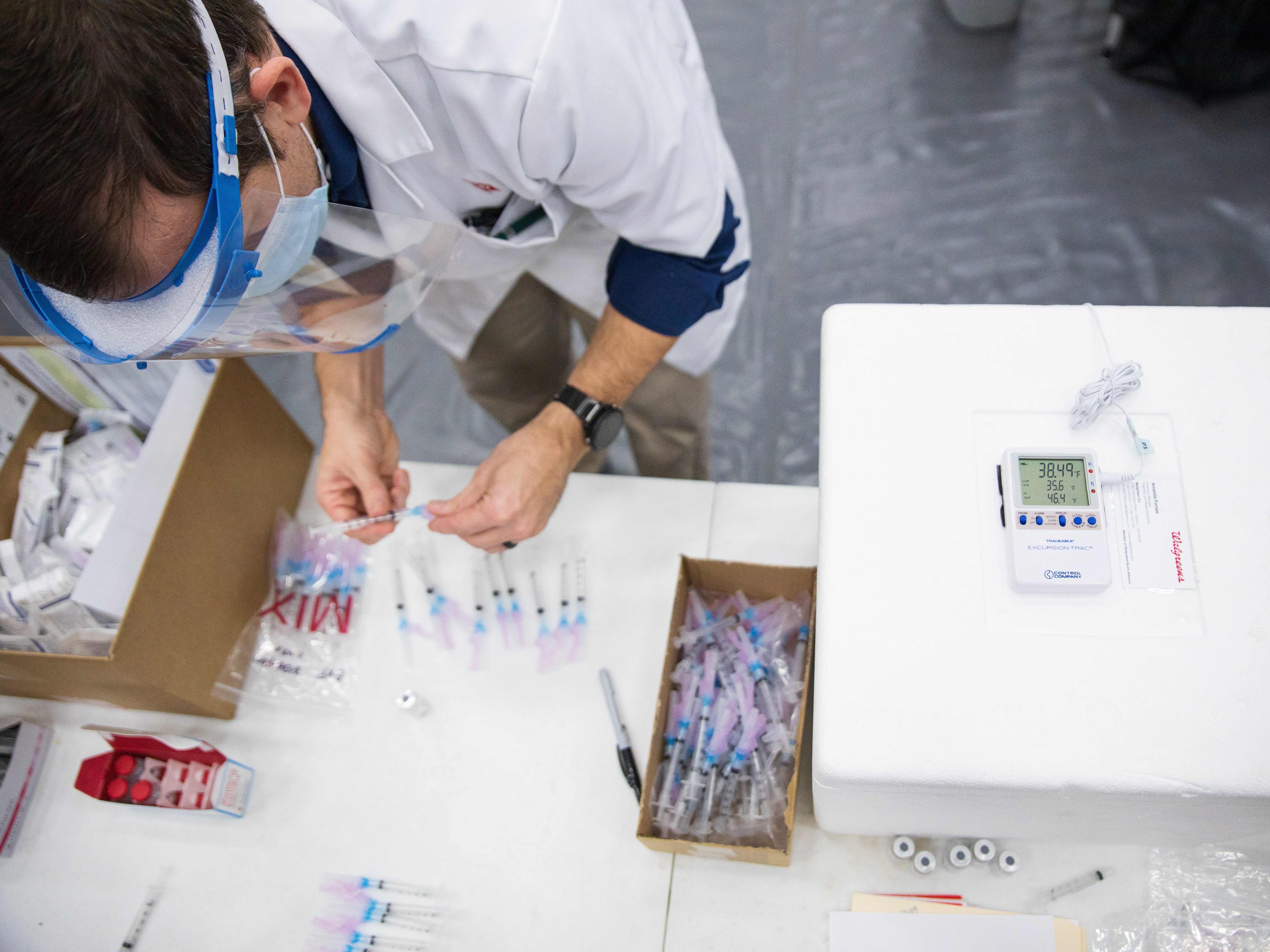 A new study finds a gap in excess deaths opened between Republicans and Democrats in 2021, after vaccine access was widened to all adults. Here, a Walgreens worker prepares vaccine shots for school staff in Dayton, Ohio, in February 2021. (AFP via Getty Images)