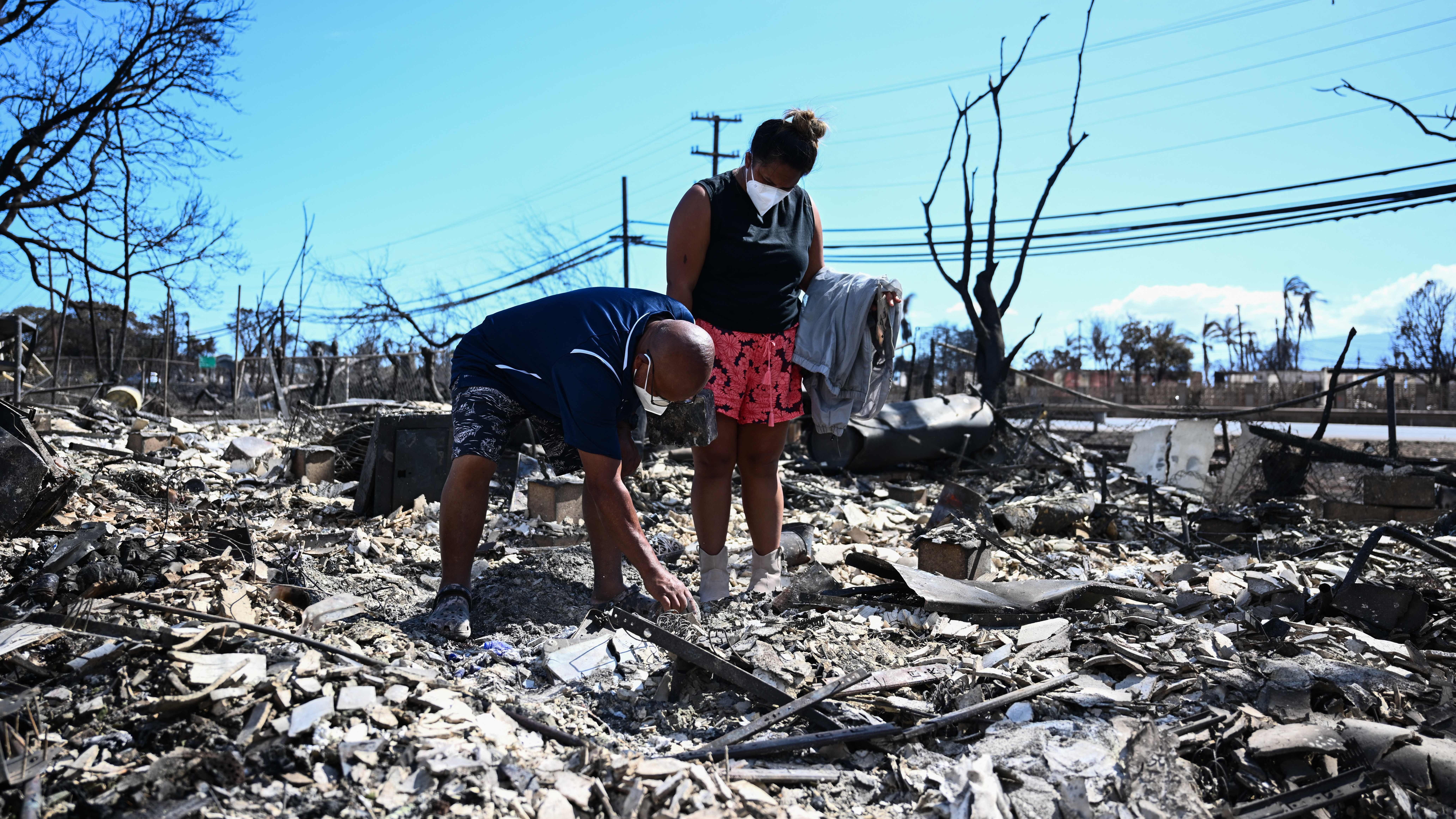 Davilynn Severson and Hano Ganer look for belongings through the ashes of their family