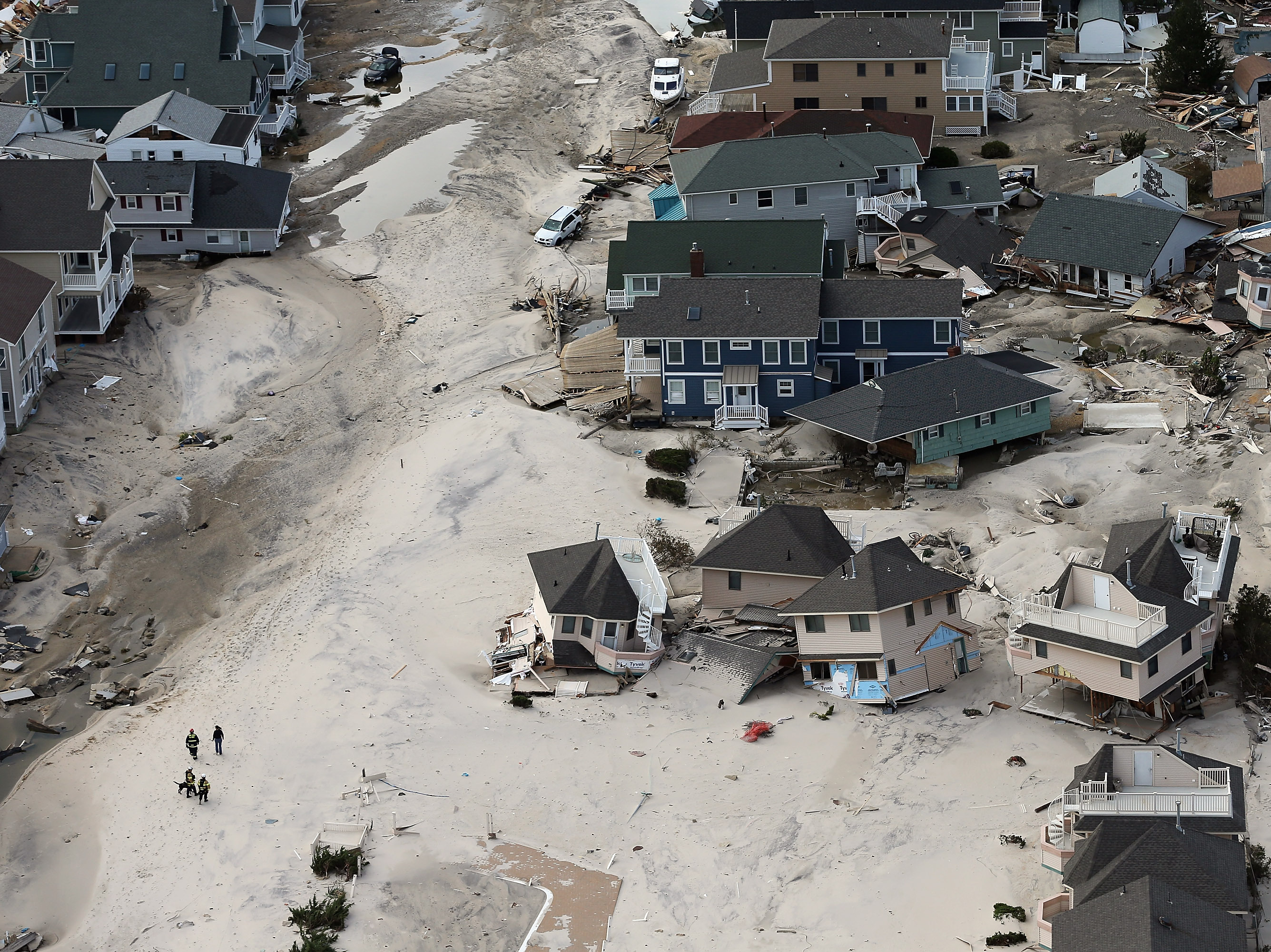 Rescue workers in Seaside Heights, New Jersey, walk past homes wrecked by Superstorm Sandy in 2012. Early reports suggested dozens of people died in the storm, but later assessments found the death toll to be at least 20 times higher. (Mario Tama/Getty Images)