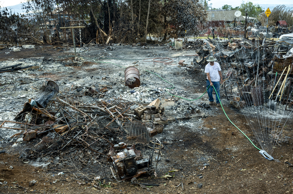 Ross Hart is working to clean up his property after his home was destroyed in the Upcountry Fire. He is running a sprinkler to keep the dust down.