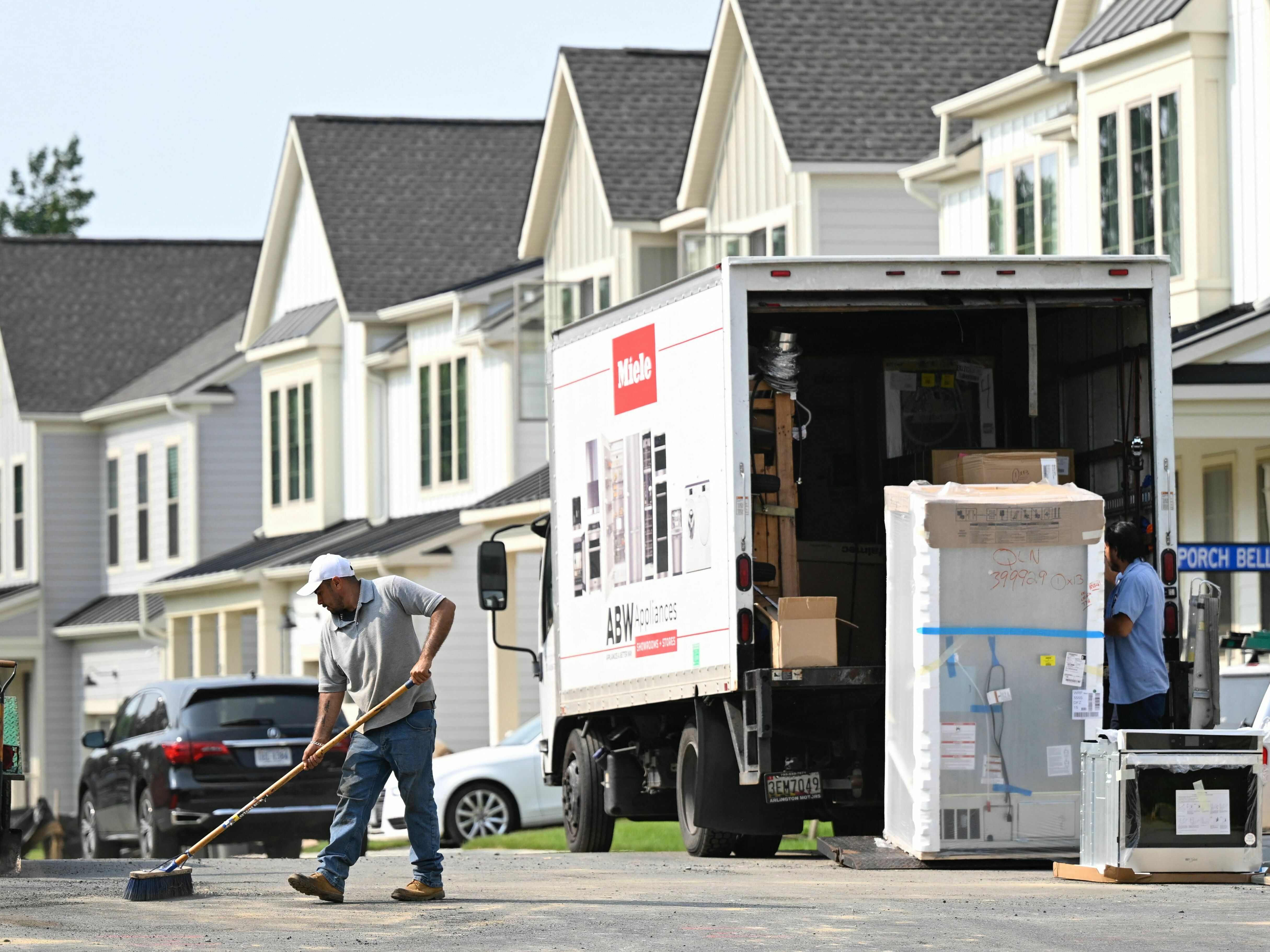 A maintenance worker sweeps the street in front of a row of new homes in Fairfax, Va., on Aug. 22. Sales of new homes are taking off as current homeowners are reluctant to sell their houses, because they would face a higher mortgage for their next one. (AFP via Getty Images)