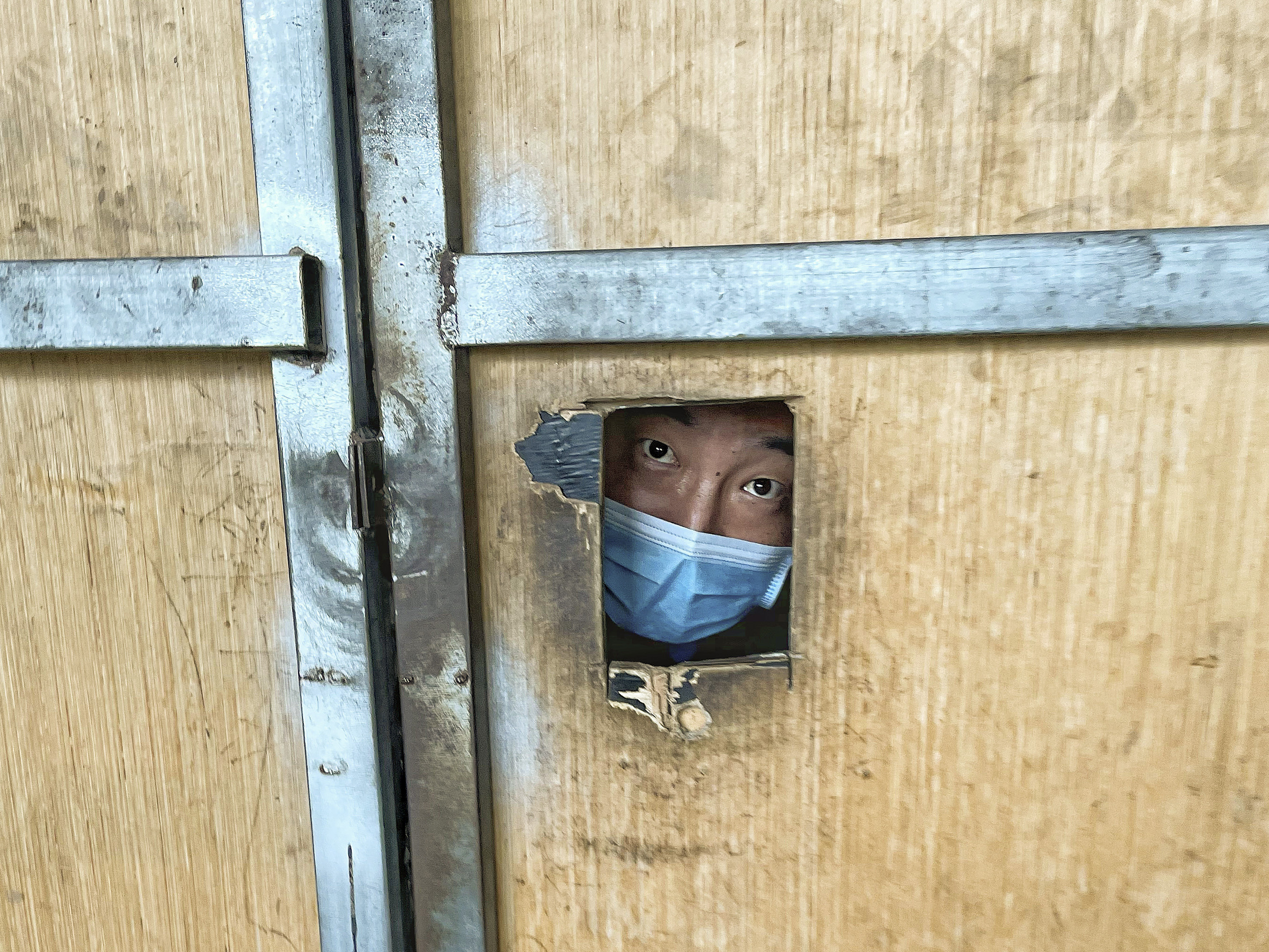 A resident looks through a hole from inside a locked-down area in Beijing on June 30, 2022. China implemented a "zero-COVID" policy that was disorienting and disruptive for global companies.