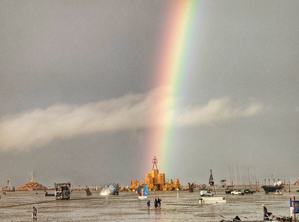 Burning Man attendee Josh Lease climbed on top of his camp's trailer to take a photo of the rainbow that emerged after heavy rains brought muddy grounds at the Black Rock City playa on Saturday.