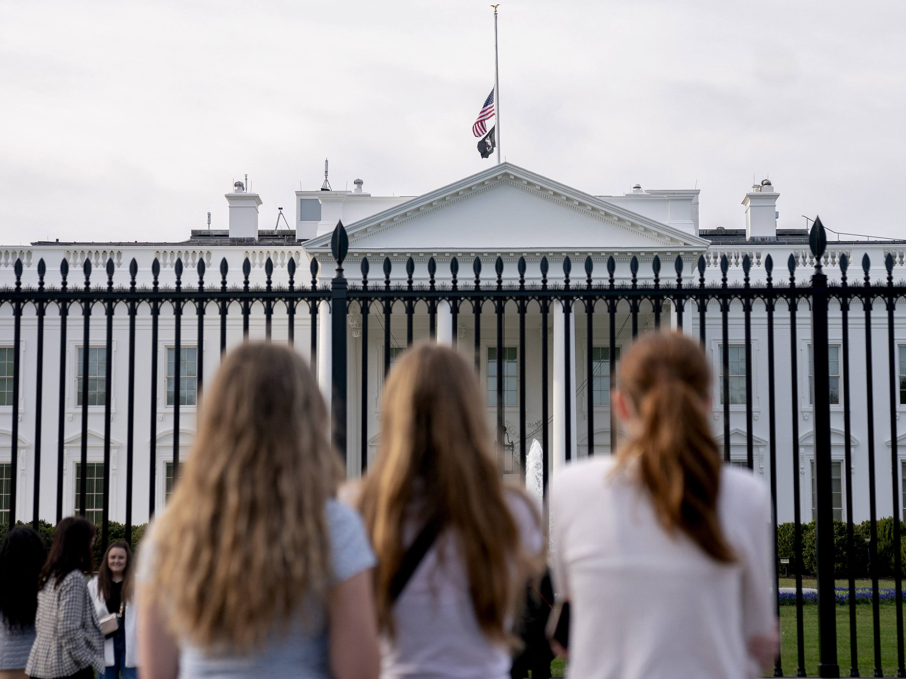 Visitors look upon the White House as the U.S. flag flies at half mast following a school shooting in Nashville, Tenn., last March. (AFP via Getty Images)