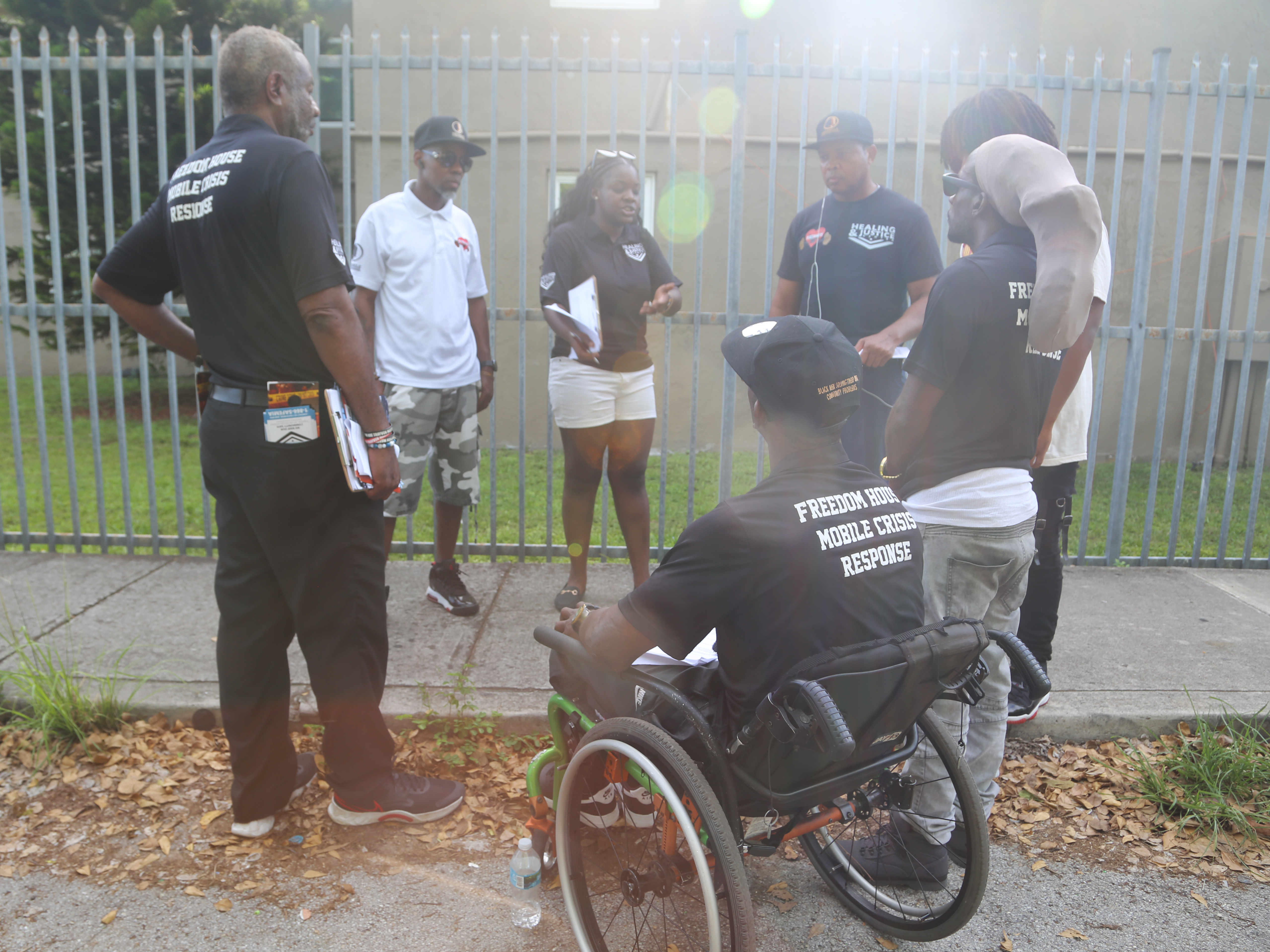 Peacemakers have a debrief before concluding their work for the day at the Lincoln Fields apartments complex in Miami, Fla. Lamont Nanton (second from left) is the group's manager and Shameka Pierce (third from left) works with the group. (WLRN)