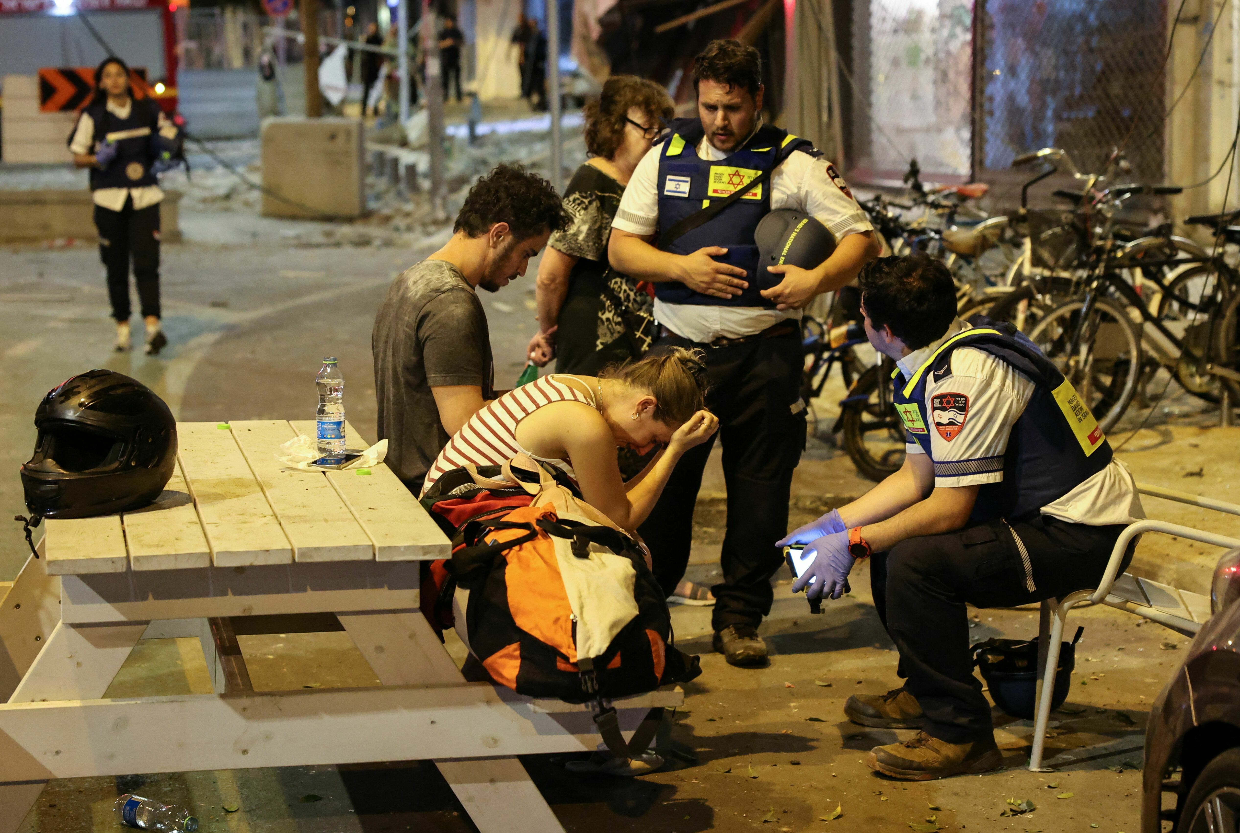Sat., Oct. 7: A young woman reacts as she speaks to Israeli rescuers in Tel Aviv.