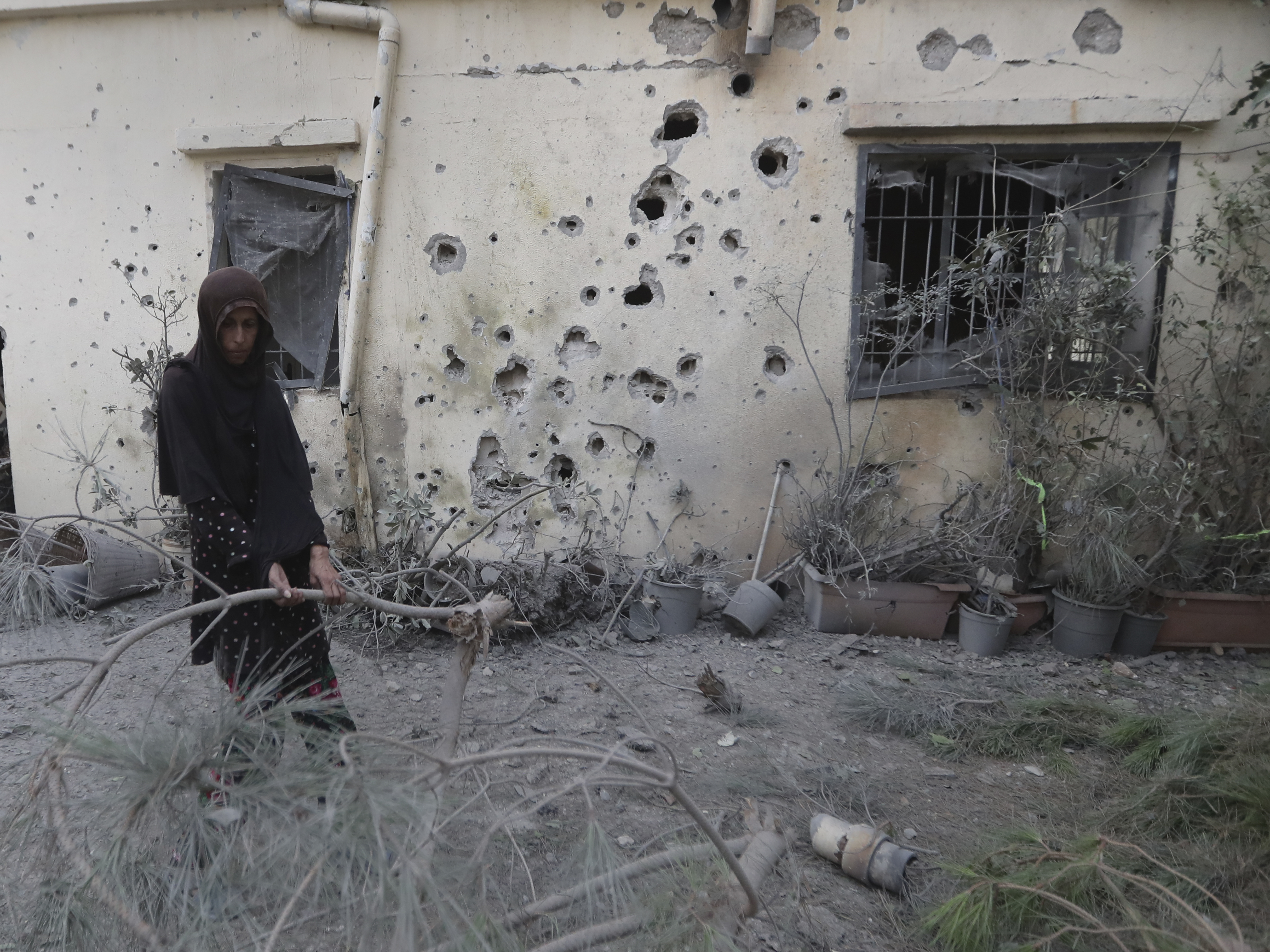 A Lebanese woman removes broken tree branches after her house was hit by Israeli shelling, in Dahaira village, South Lebanon, Oct. 9, 2023.