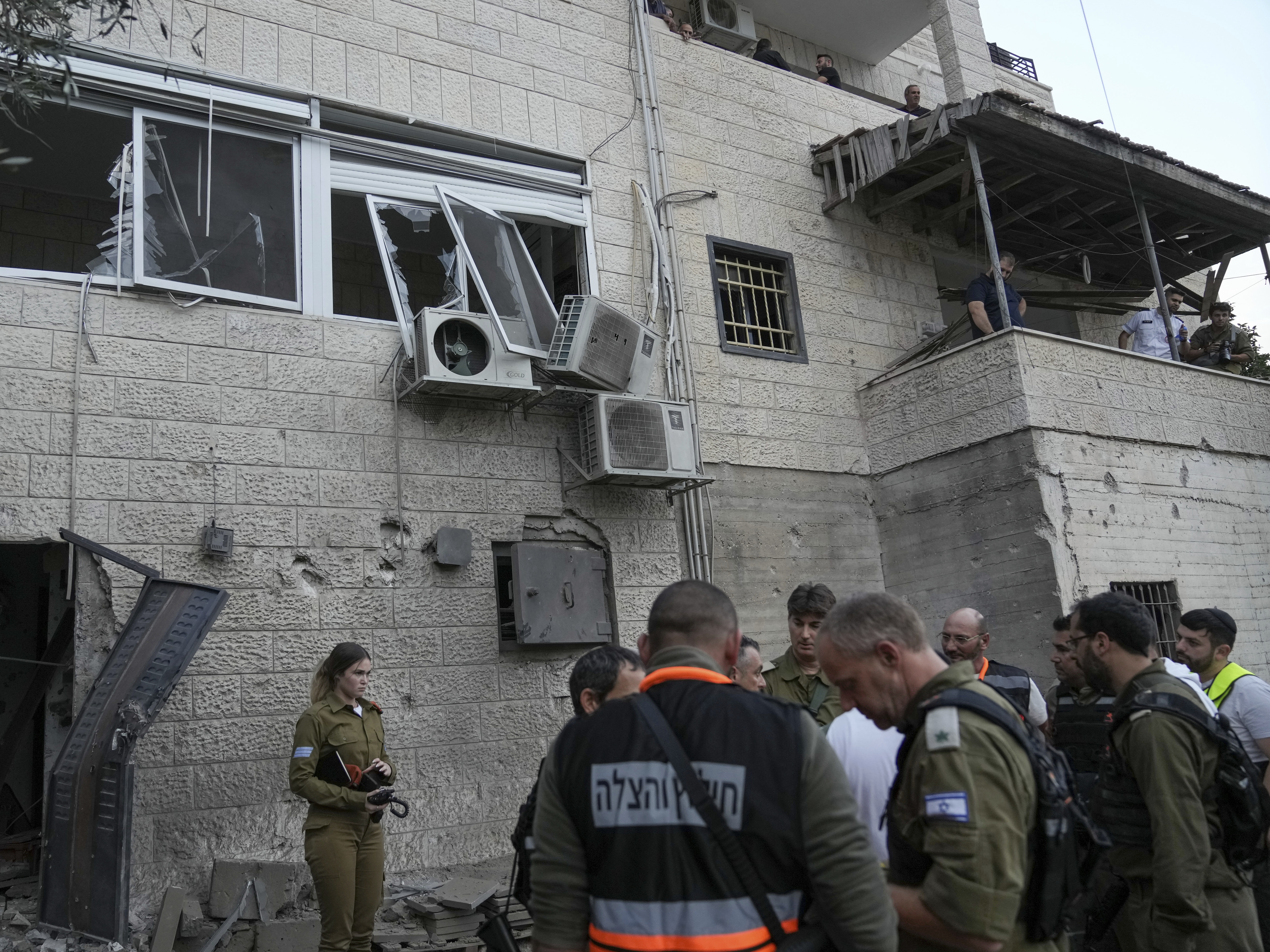 Israeli security forces inspect a damaged house after it was hit by a rocket fired from the Gaza Strip, in the village of Abu Ghosh near Jerusalem, Oct. 9, 2023.