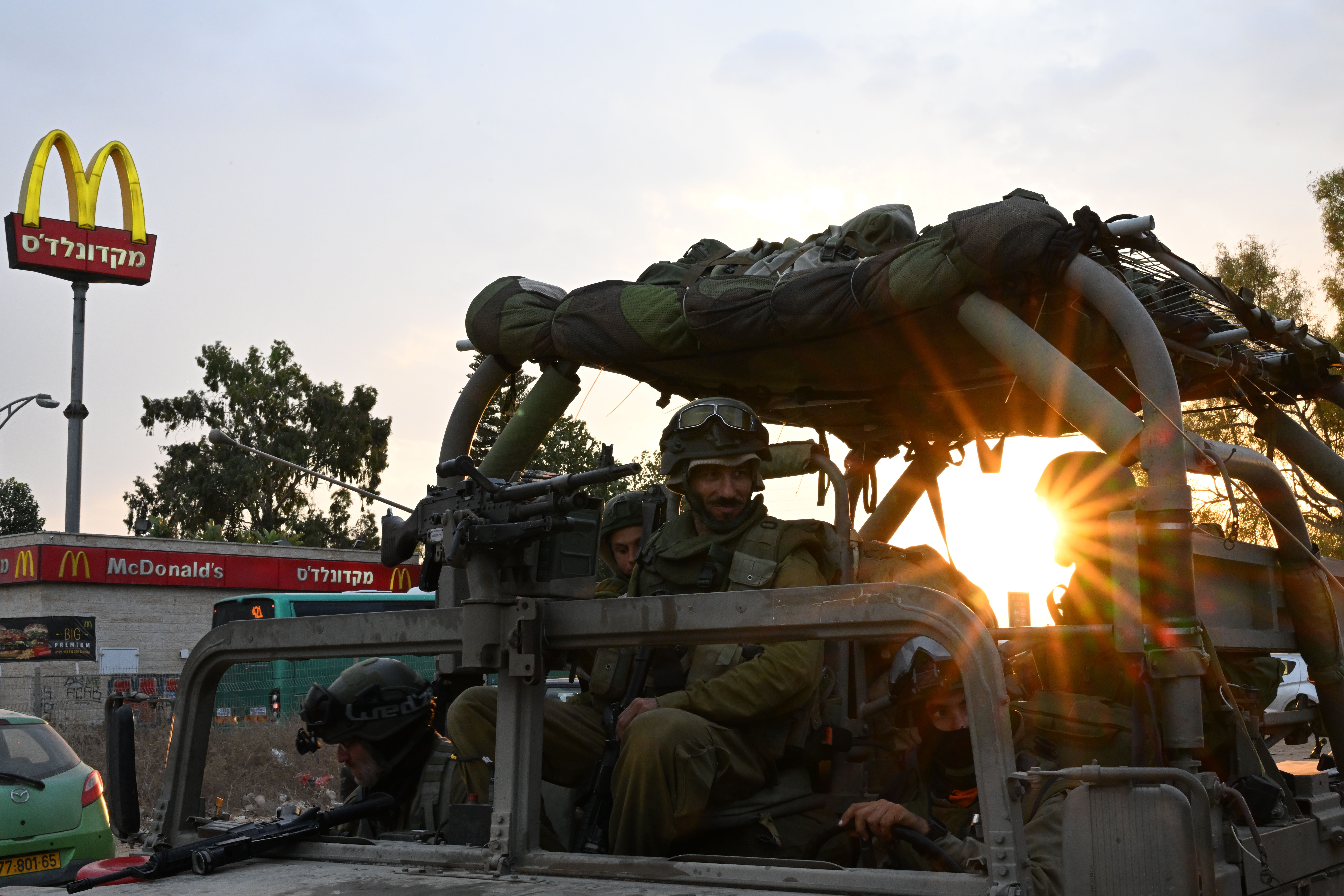At a rest stop near Hamas attack sites, Israelis rush to help families and soldiers 10 Israeli soldiers and vehicles at gas station.