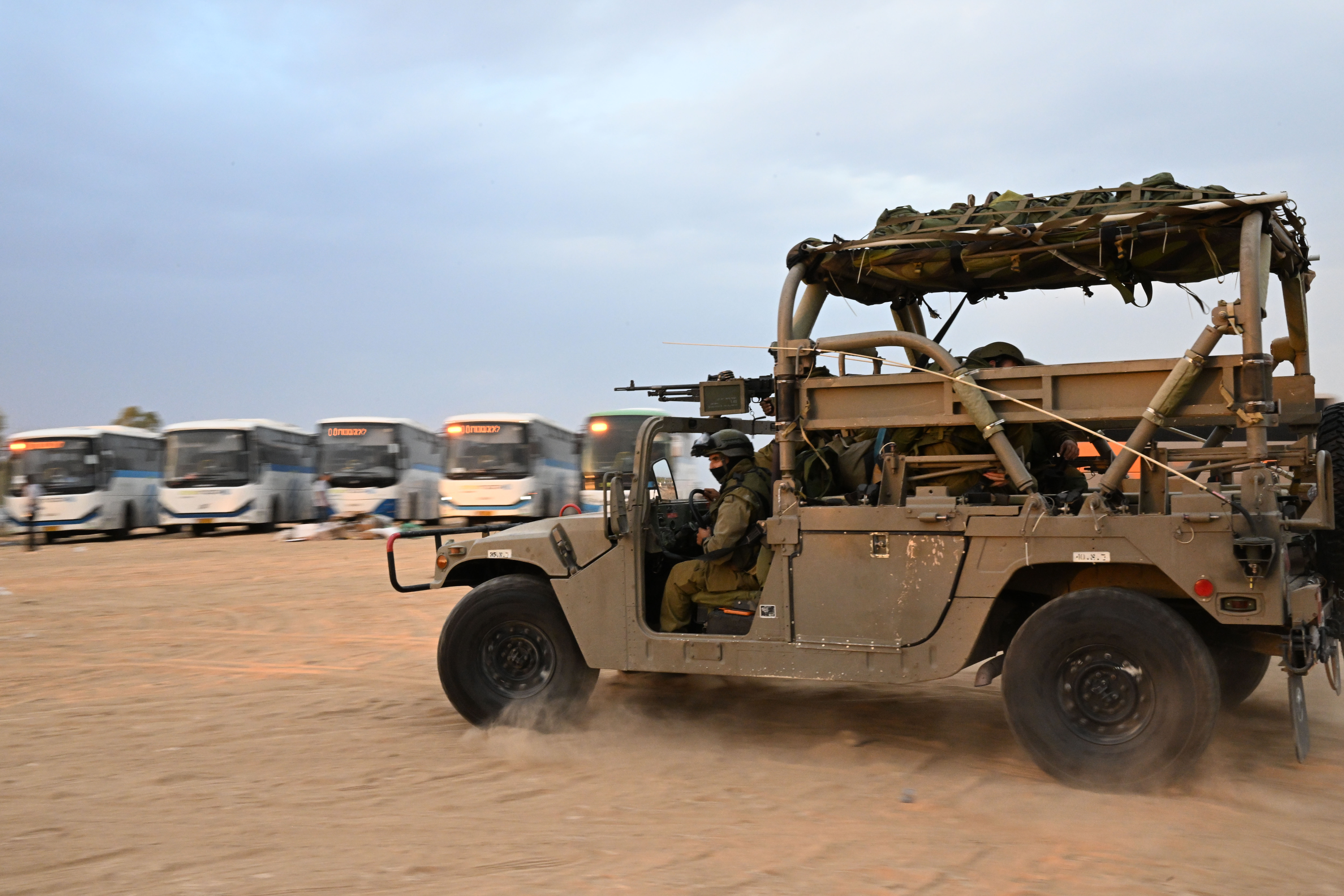 At a rest stop near Hamas attack sites, Israelis rush to help families and soldiers 2 Israeli soldiers and vehicles at a gas station.