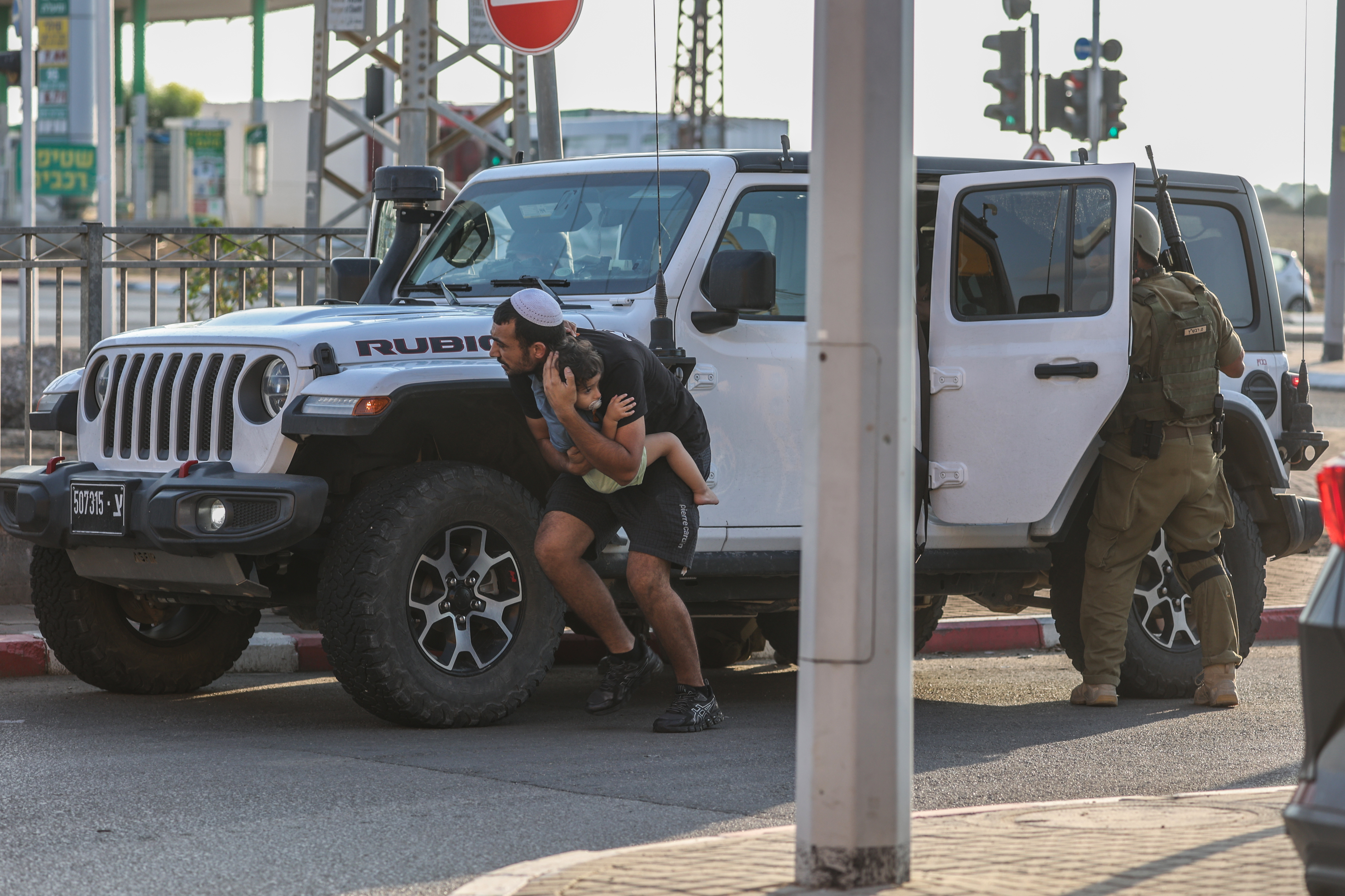 Tues., Oct. 10: A man holds his child while taking cover behind a vehicle amid a rocket attack from Gaza.