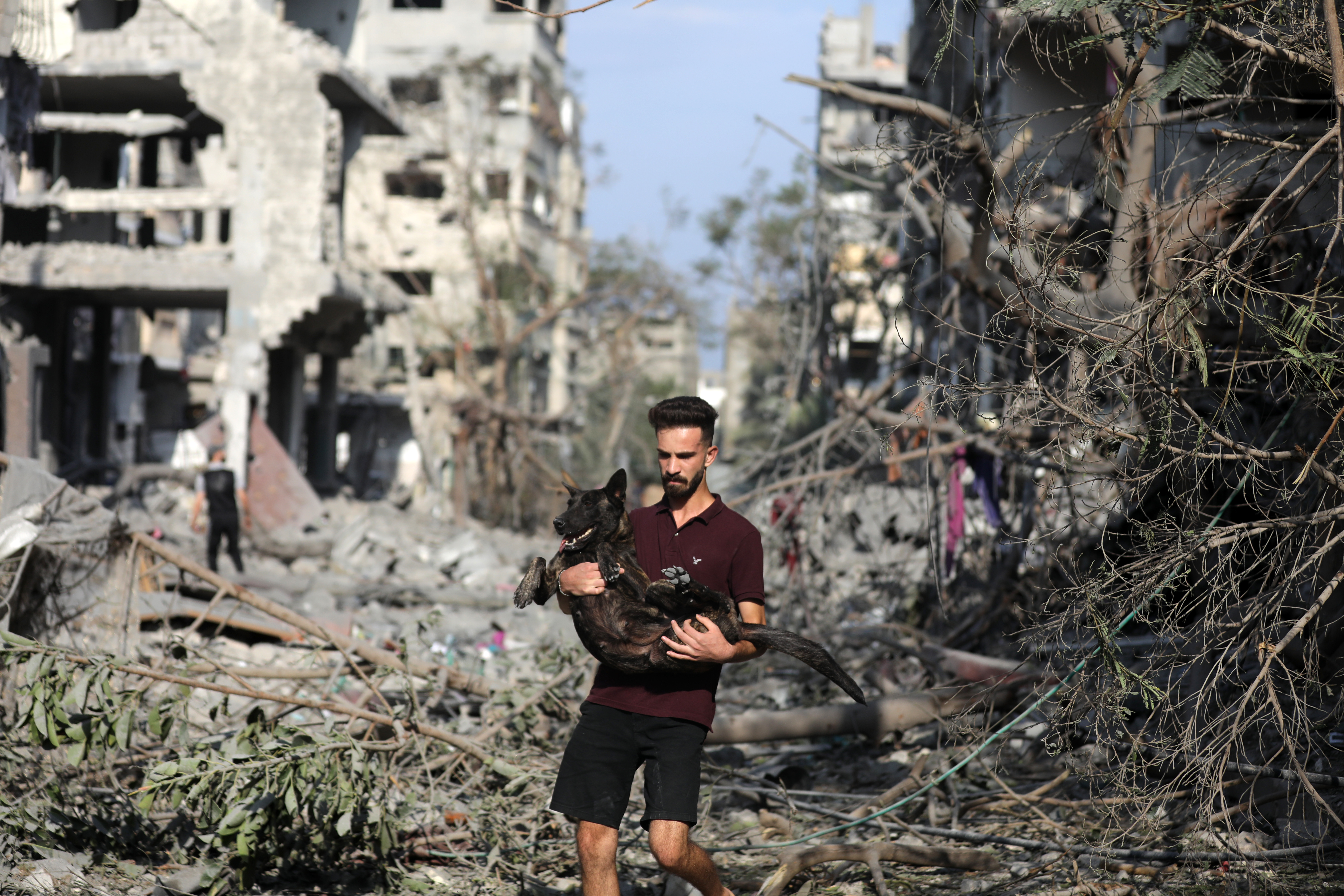 Wed., Oct. 11: A man carrying his dog as he leaves a bombed area following overnight Israeli airstrikes in Gaza City.