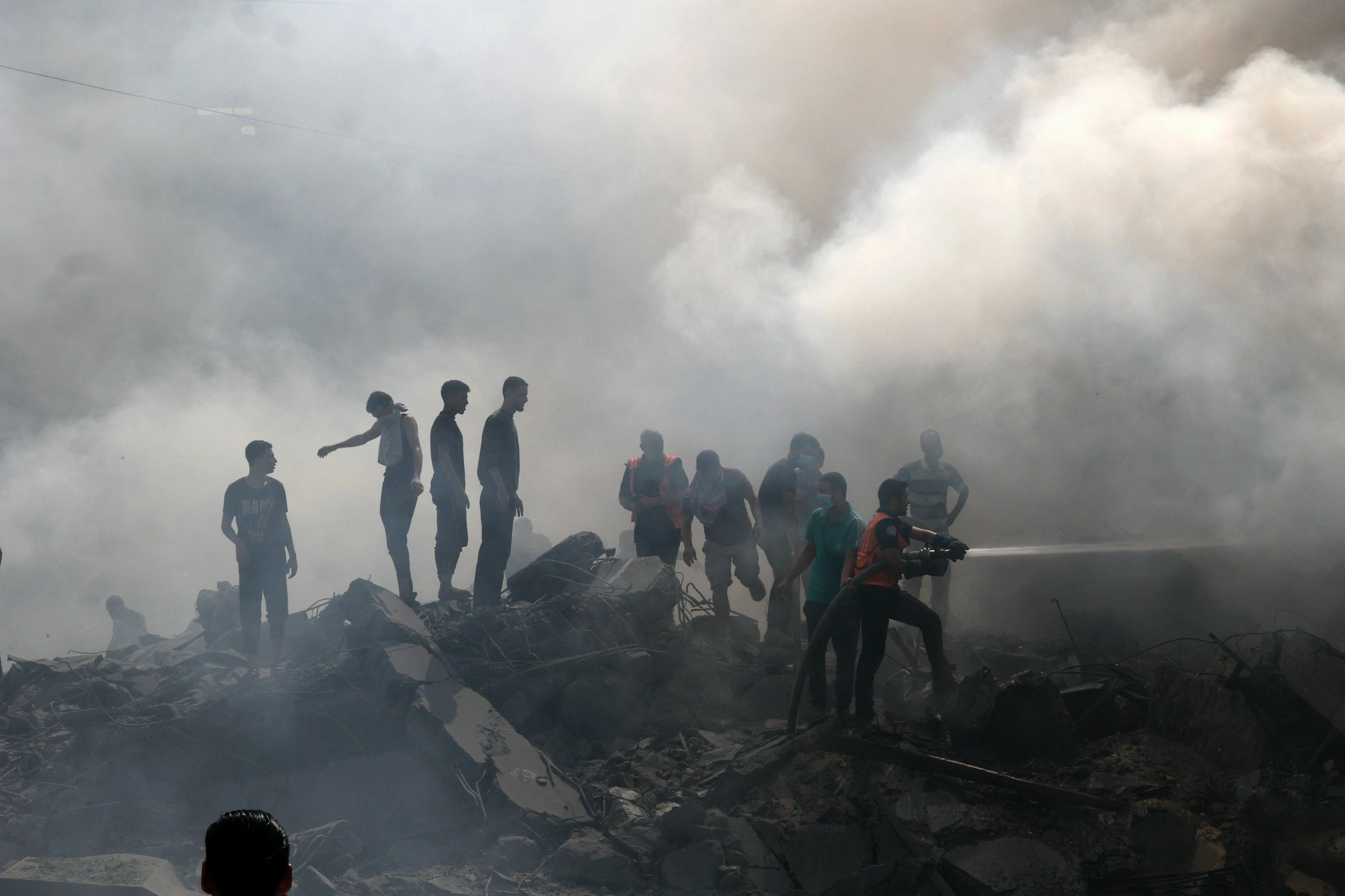 Thu., Oct. 12: Palestinians stand on the rubble of a building as a civil defence worker uses a water hose following an Israeli strike in the southern Gaza Strip.