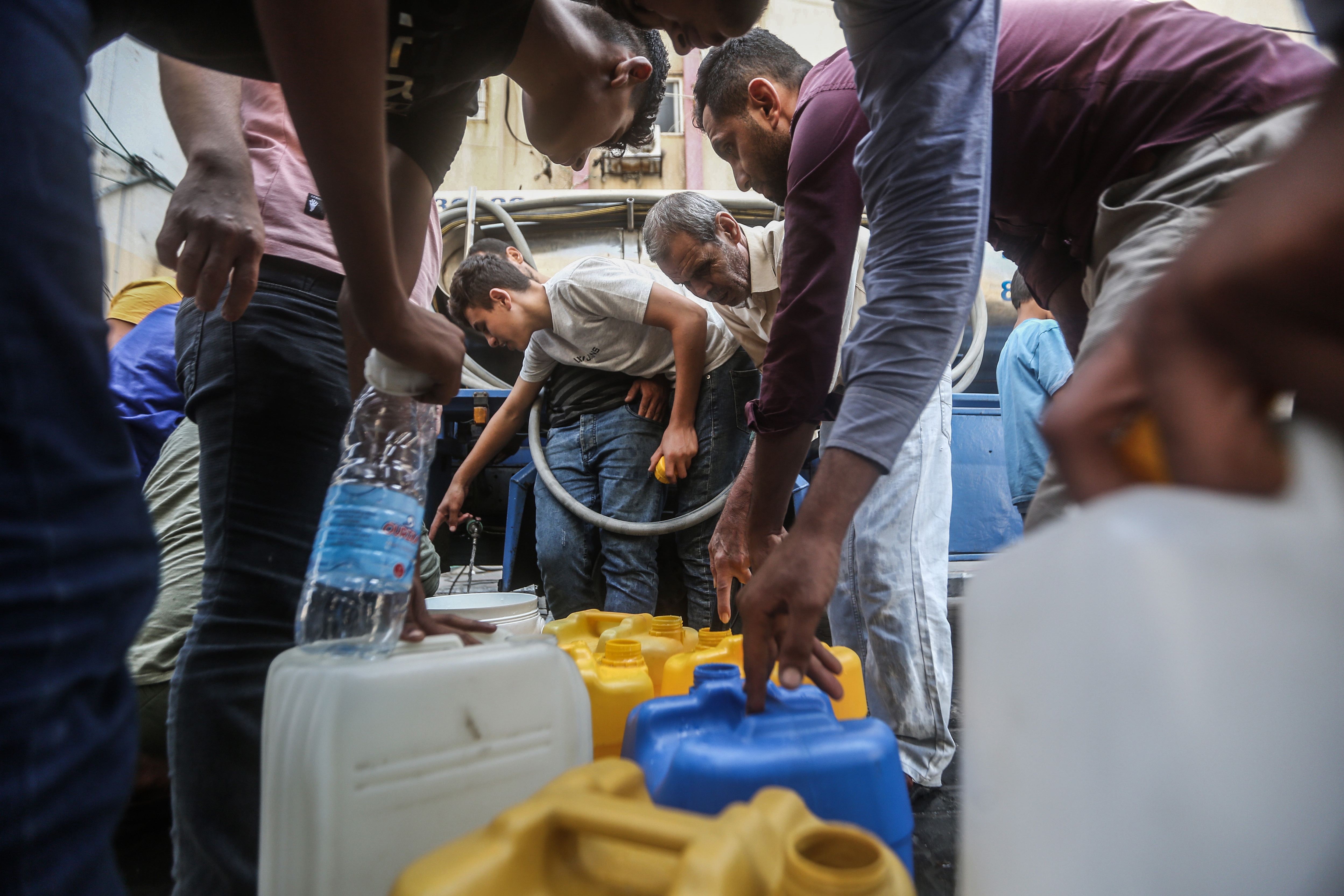 Thu., Oct. 12: Palestinians fill containers with drinking water from a water distribution vehicle, amid the water crisis caused by the Israeli siege on the Gaza Strip.