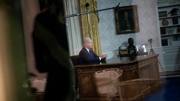 President Biden is seen through the window of the Oval Office of the White House during his address to the nation on Thursday night.