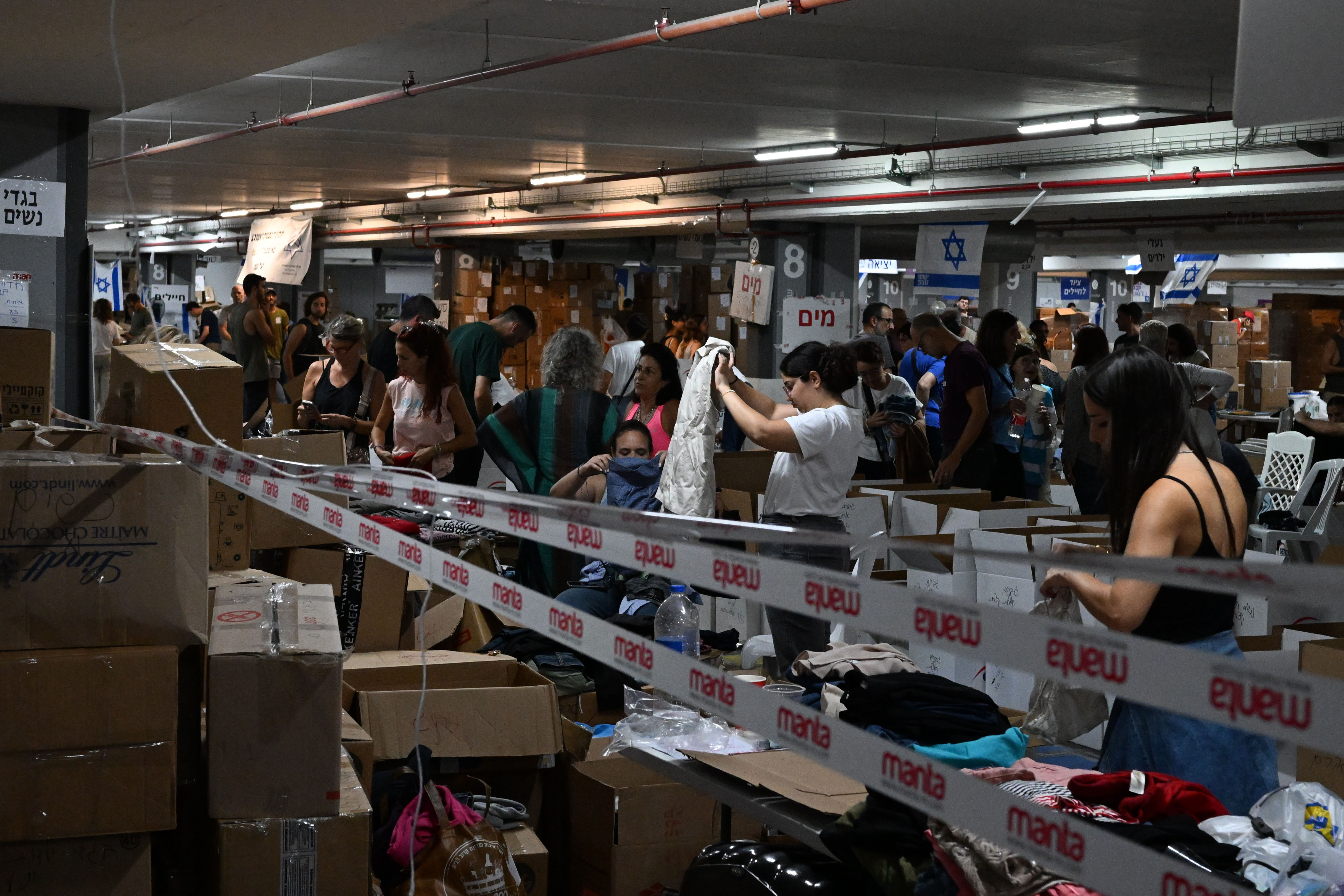 In the underground parking lot at the Expo Tel Aviv International Convention Center, thousands of volunteers help sort and distribute baby clothes, books, winter clothes, and more. (Tanya Habjouqa/NOOR for NPR)
