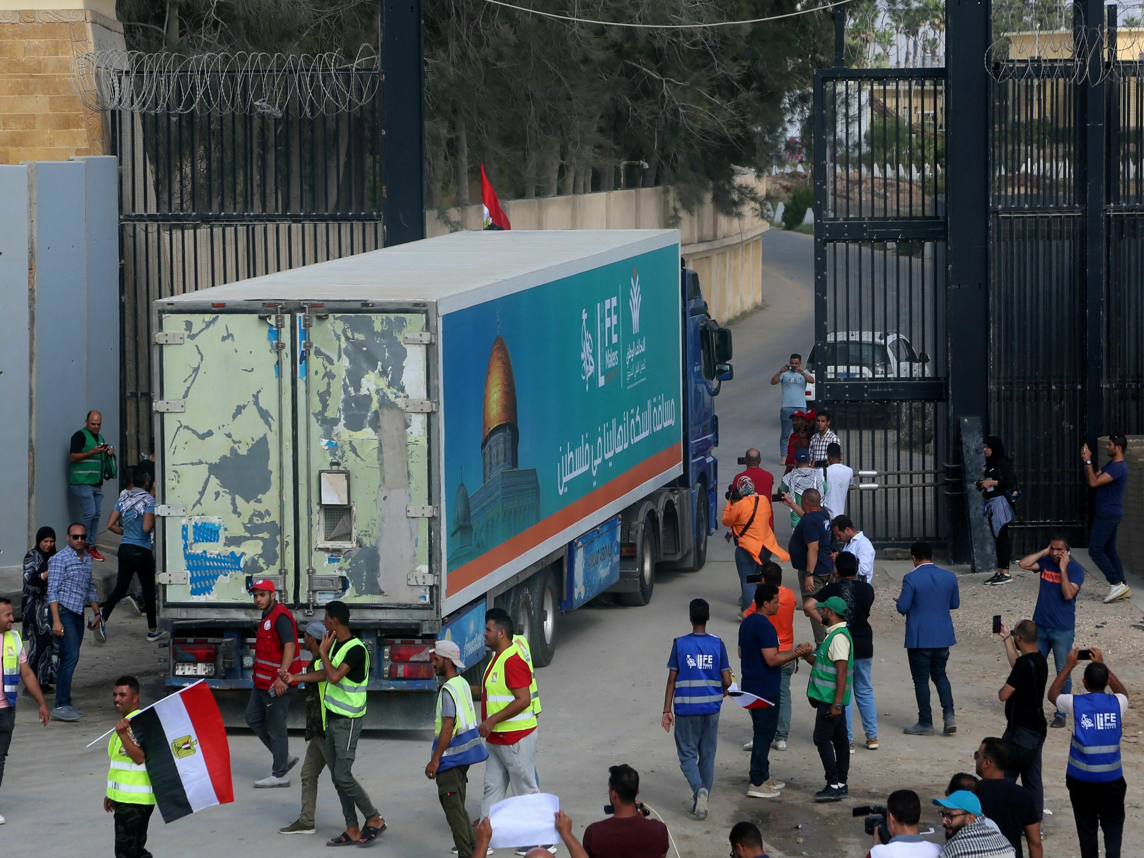 People on the Egyptian side of the Rafah border crossing watch as a convoy of lorries carrying humanitarian aid crosses to the Gaza Strip on Sunday. (AFP via Getty Images)