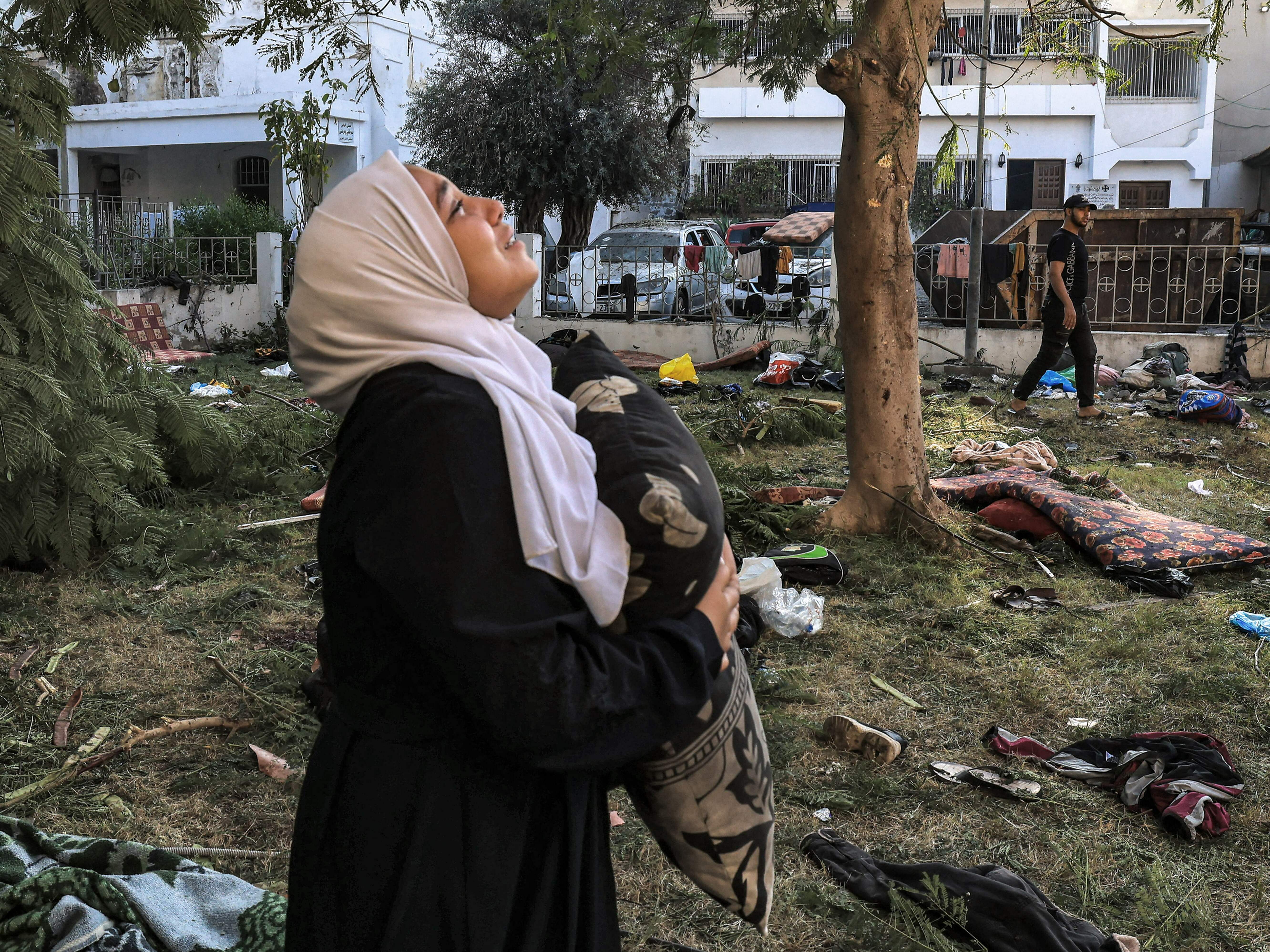 A woman holds a pillow near the Al Ahli Arab Hospital in Gaza City, the site of a blast that killed hundreds on October 17. In the aftermath, Hamas and Israel traded blame. (AFP via Getty Images)