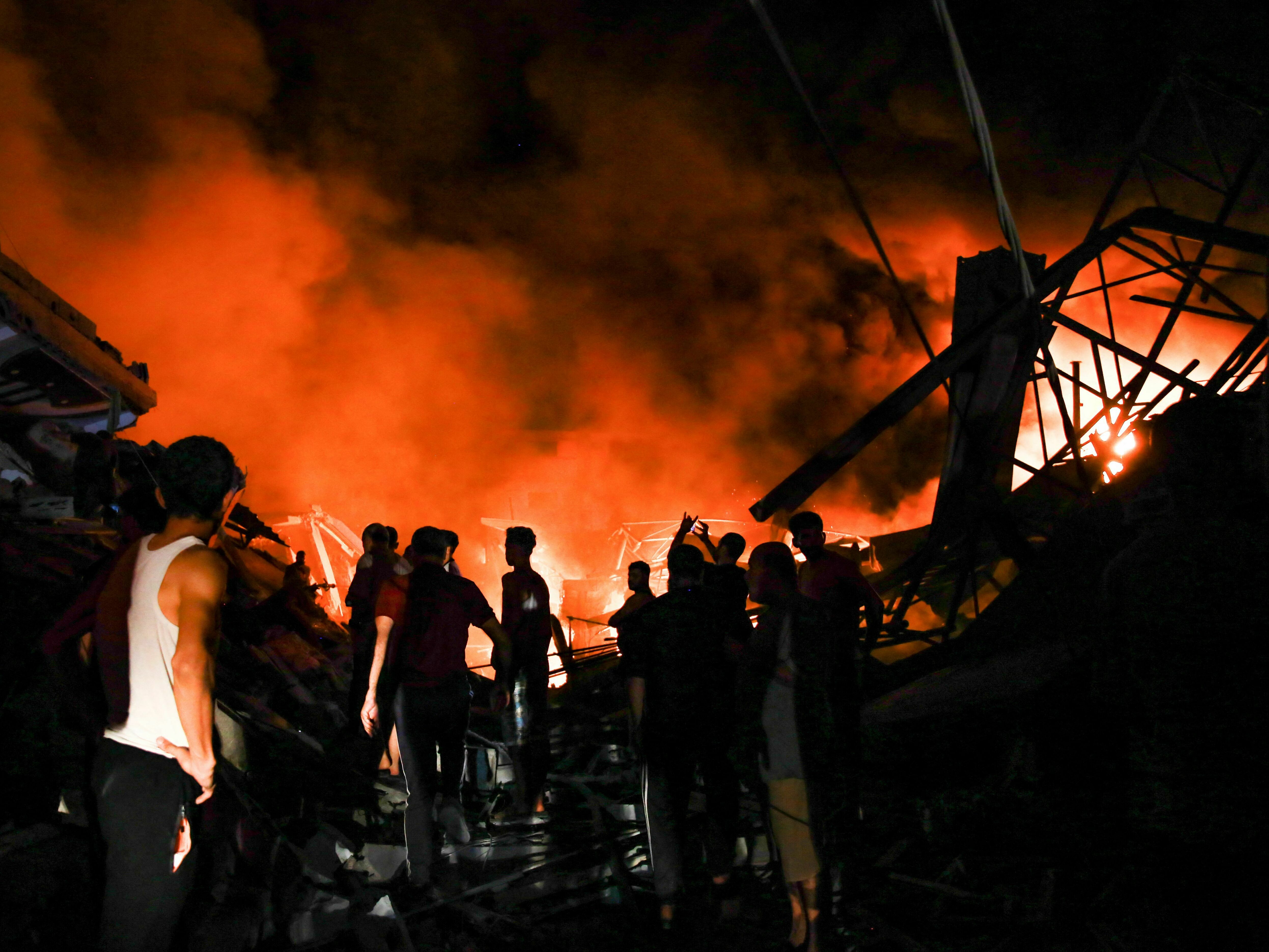 Smoke and fire rise from buildings as people gather in the aftermath of an Israeli strike on Gaza City on Thursday. (AFP via Getty Images)