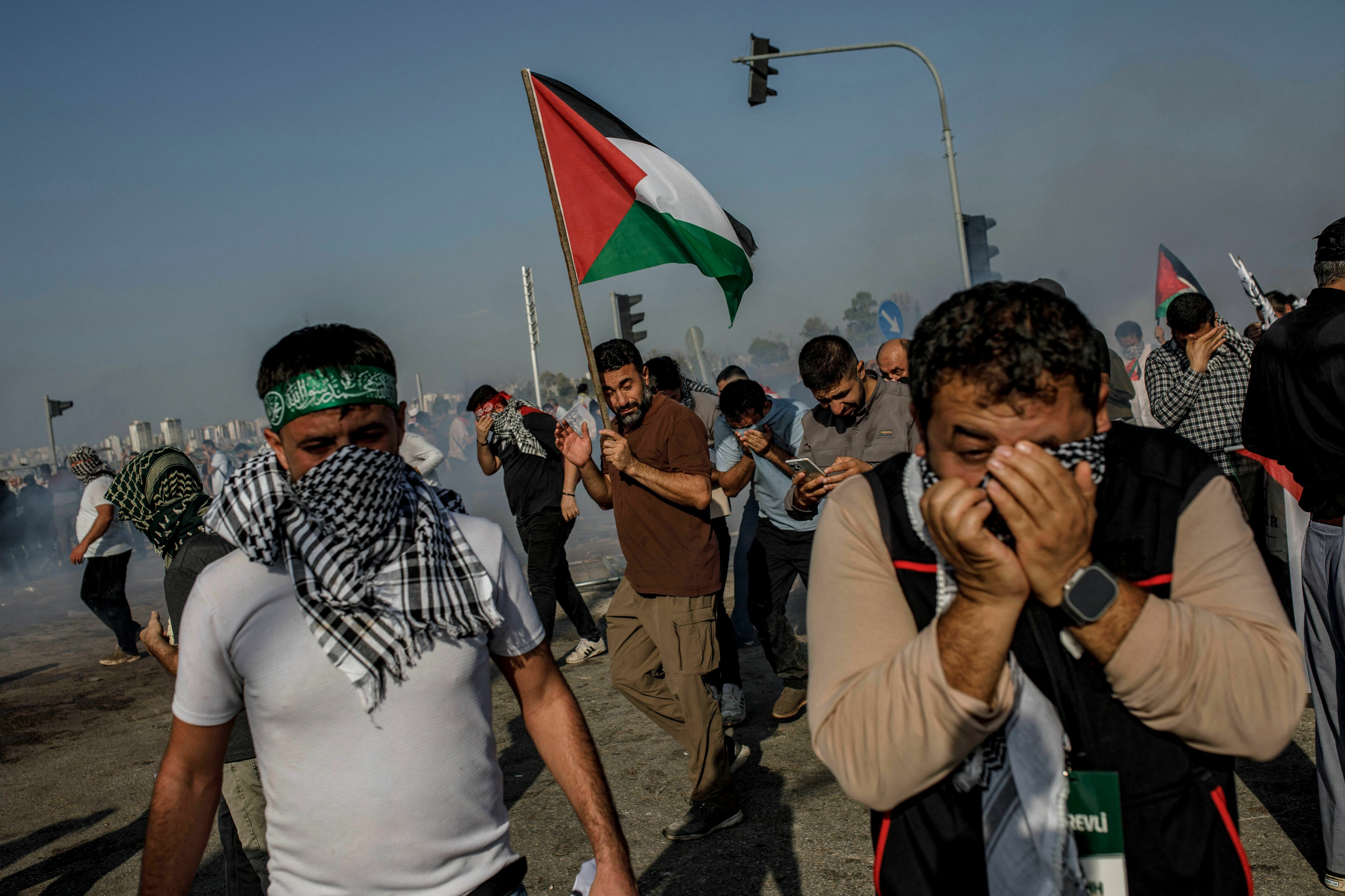 Protestors cover their faces to protect from the tear gas fired by Turkish anti-riot police during a Pro-Palestinian demonstration against US secretary of state's visit to Turkey near the Incirlik Air Base, housing US forces, in Adana, southern Turkey, on Sunday.