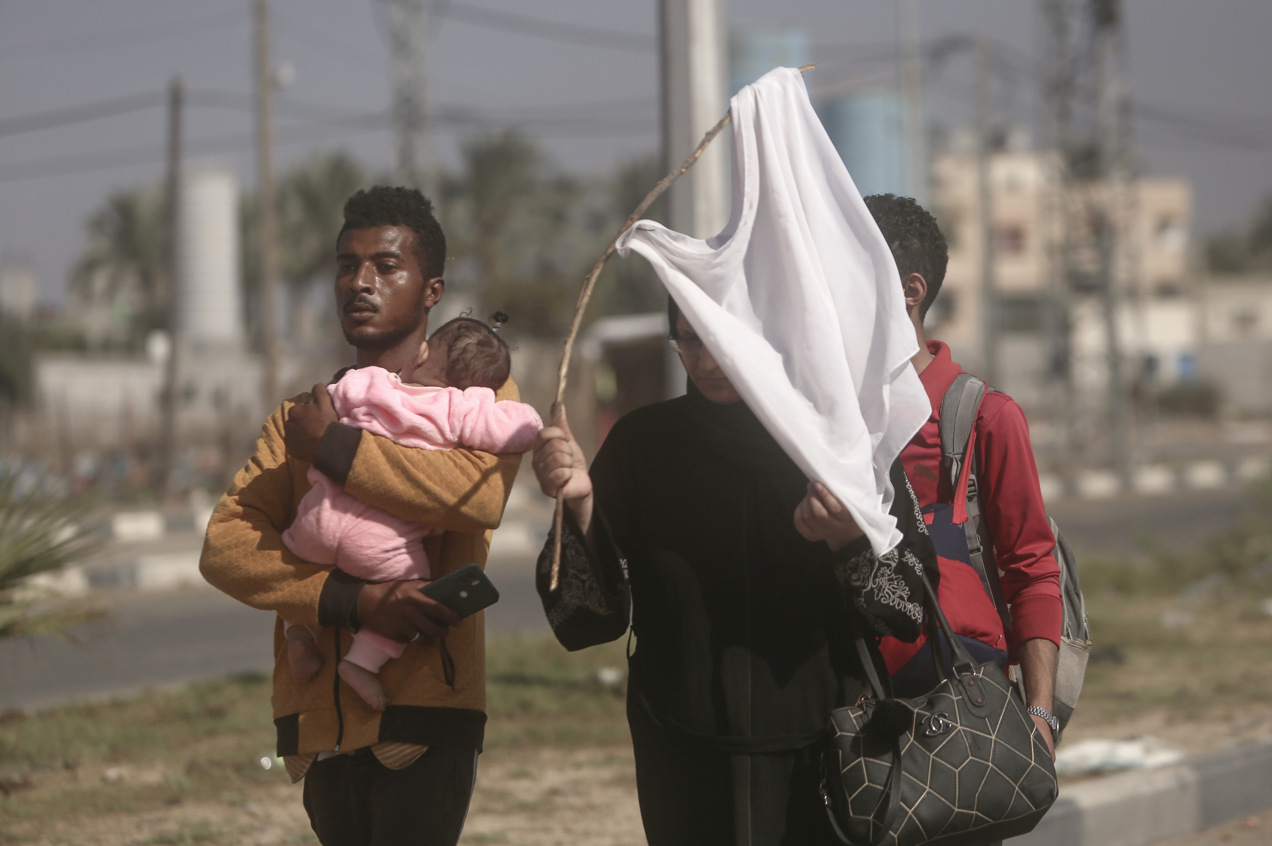 Tues., Nov. 7: A woman holds up a stick with a shirt attached as a white flag to prevent being shot, as Palestinians flee Gaza City to the southern Gaza Strip on Salah al-Din street in Bureij.