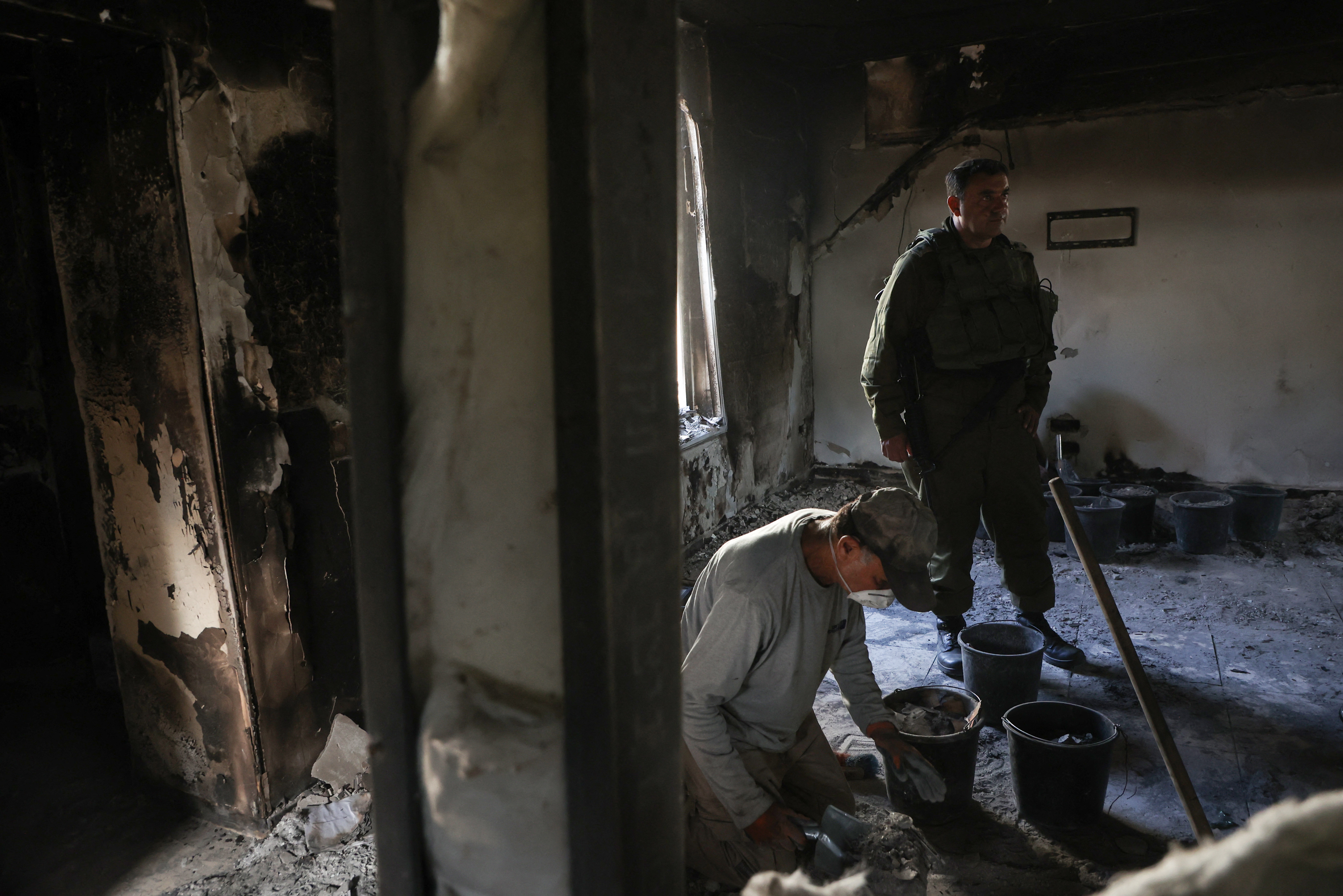 Thurs., Nov. 9: An Israeli soldier stands near an archaeologist from the Israel Antiquities Authority, as he collects ashes from a burnt out house inside Kibbutz Nir Oz in southern Israel, to identify residents who went missing during the Oct. 7 attack by Hamas militants.
