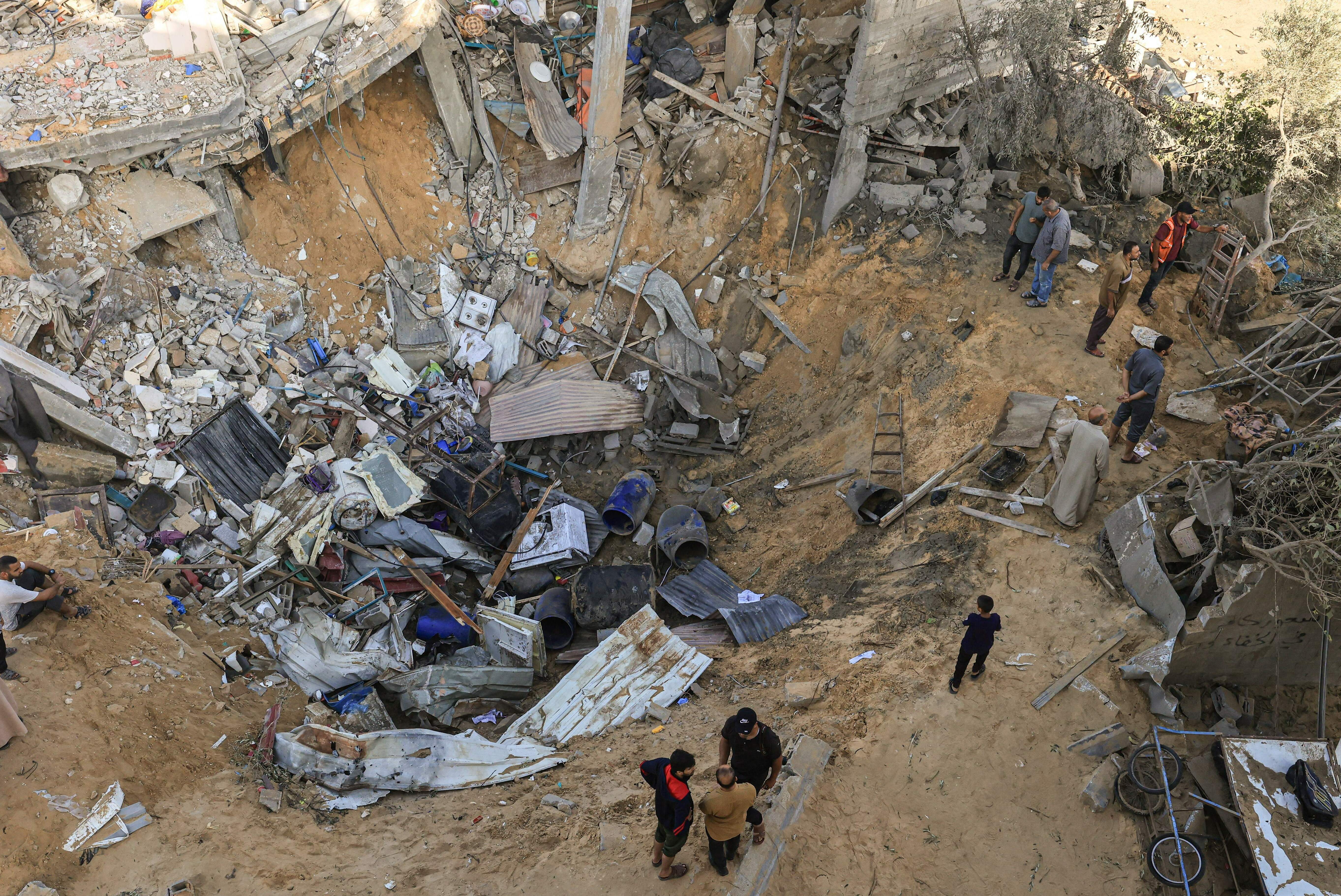 Fri., Nov. 10: Palestinians stand at the edge of a crater following the Israeli bombardment of Rafah in the southern Gaza Strip.