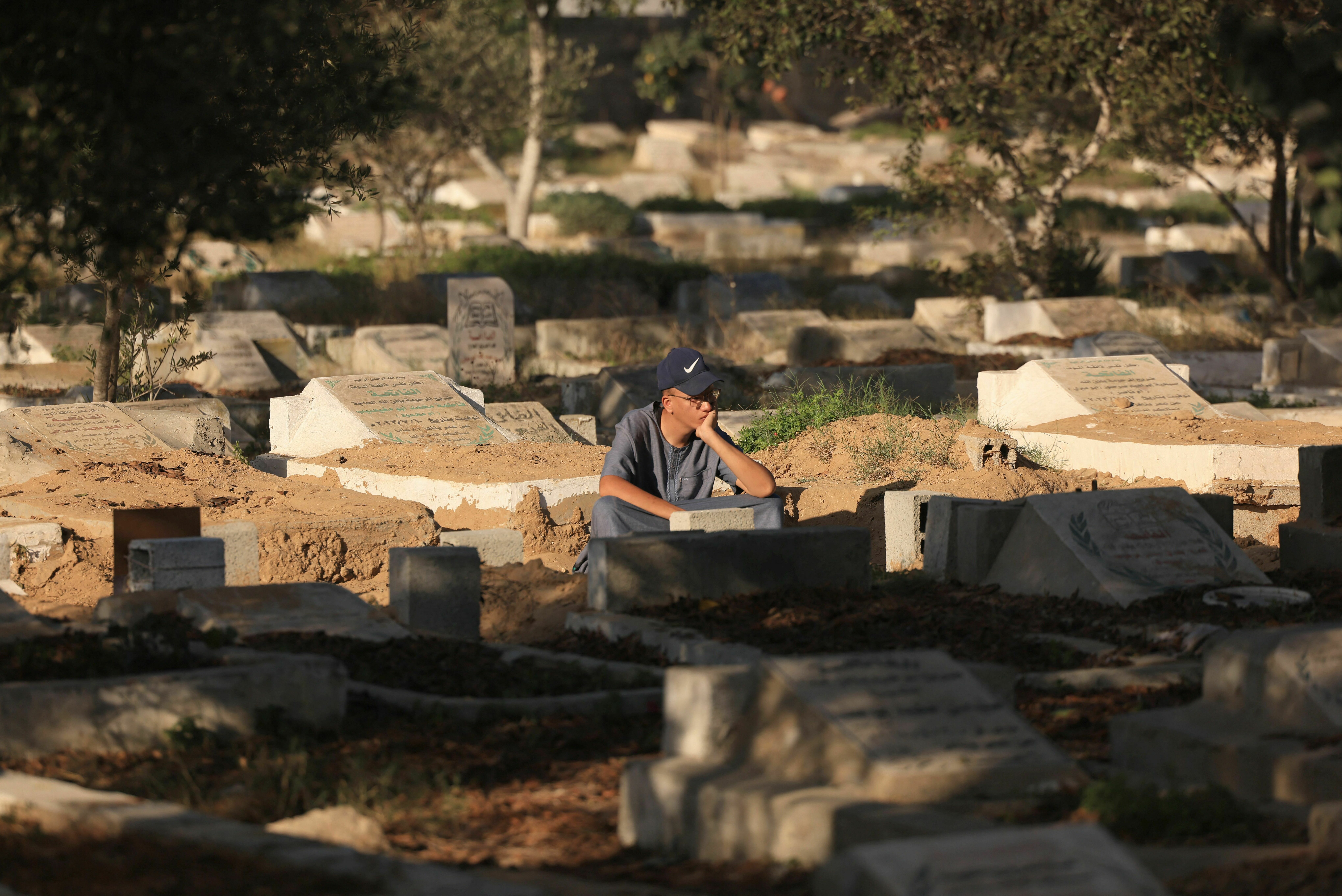 Fri., Nov. 10: A Palestinian man sits next to graves at the Deir el-Balah cemetery, in the central Gaza Strip, amid the ongoing battles between Israel and the Palestinian Islamist group Hamas.