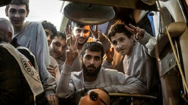 People gesture from a Red Cross bus carrying Palestinian prisoners released from Israeli jails in exchange for hostages released by Hamas from the Gaza Strip, in Ramallah, in the occupied West Bank, on Sunday.