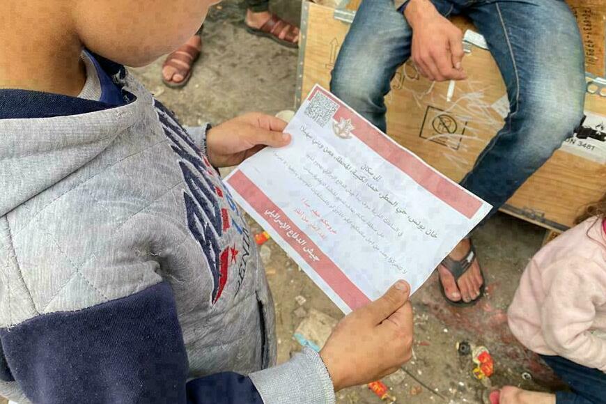 A boy in Rafah, Gaza, holds a leaflet dropped by an Israeli aircraft that advises residents to stay sheltered ahead of planned airstrikes. (NPR)
