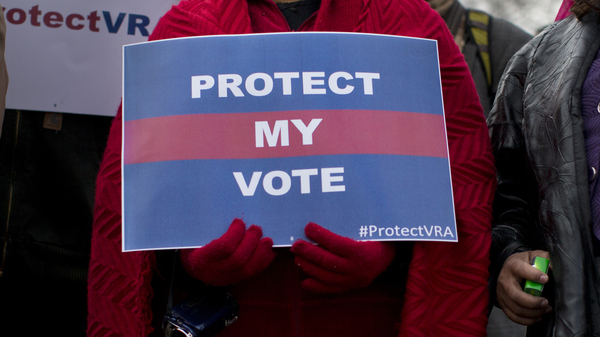 People carrying signs in support of the Voting Rights Act line up outside the U.S. Supreme Court in Washington, D.C., in 2013.