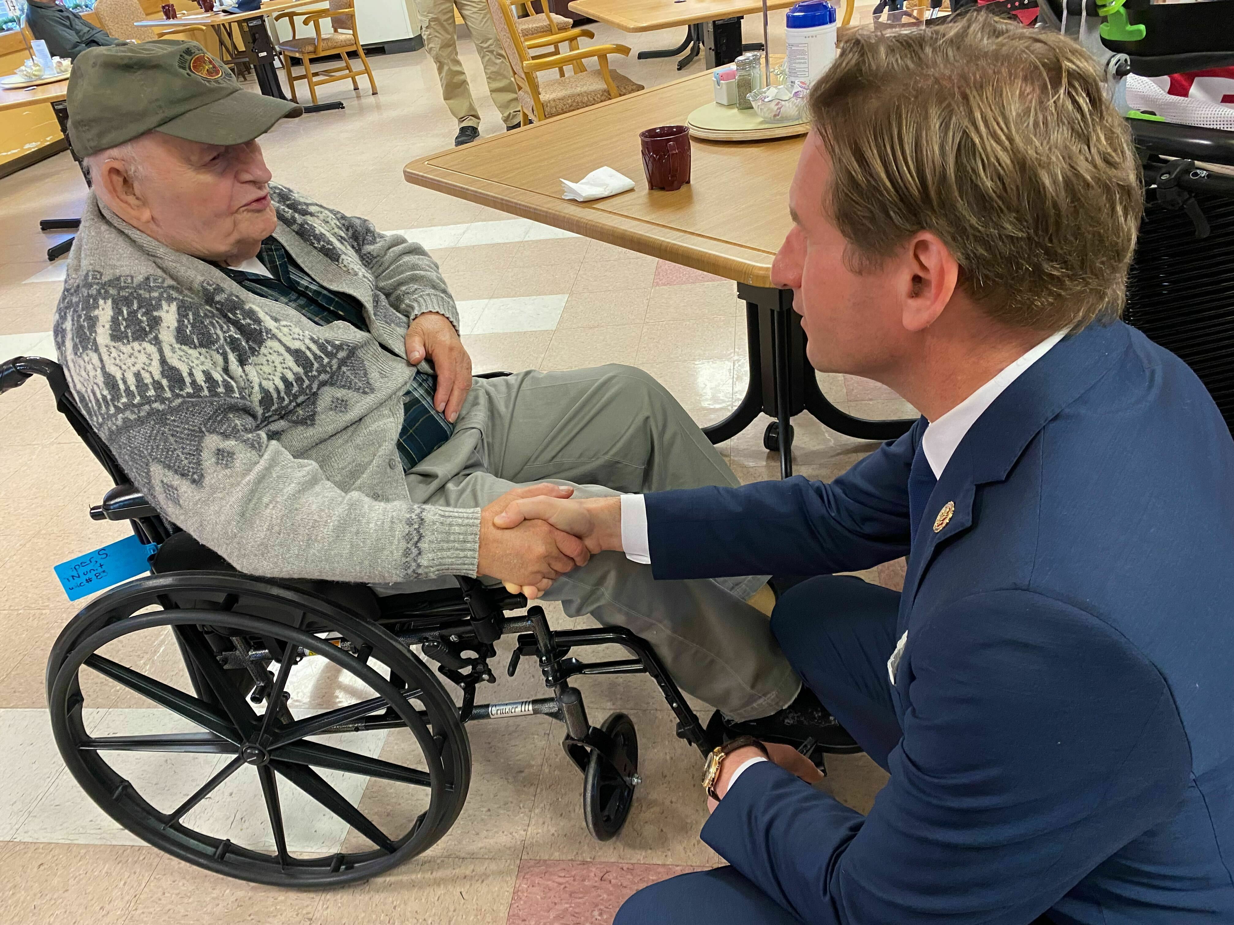 Stanley Piper talks with Rep. Dean Phillips, D-Minn., at the New Hampshire Veterans Home in Tilton, N.H. on Dec. 8, 2023. (NPR)