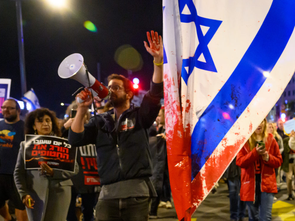 A protester with red paint on his hand marches through the streets after demonstrating outside the Israel Defense Forces headquarters on Friday in Tel Aviv, Israel. Earlier, the IDF had said its forces accidentally killed three hostages being held in Gaza when it mistakenly identified them as potential threats. (Getty Images)