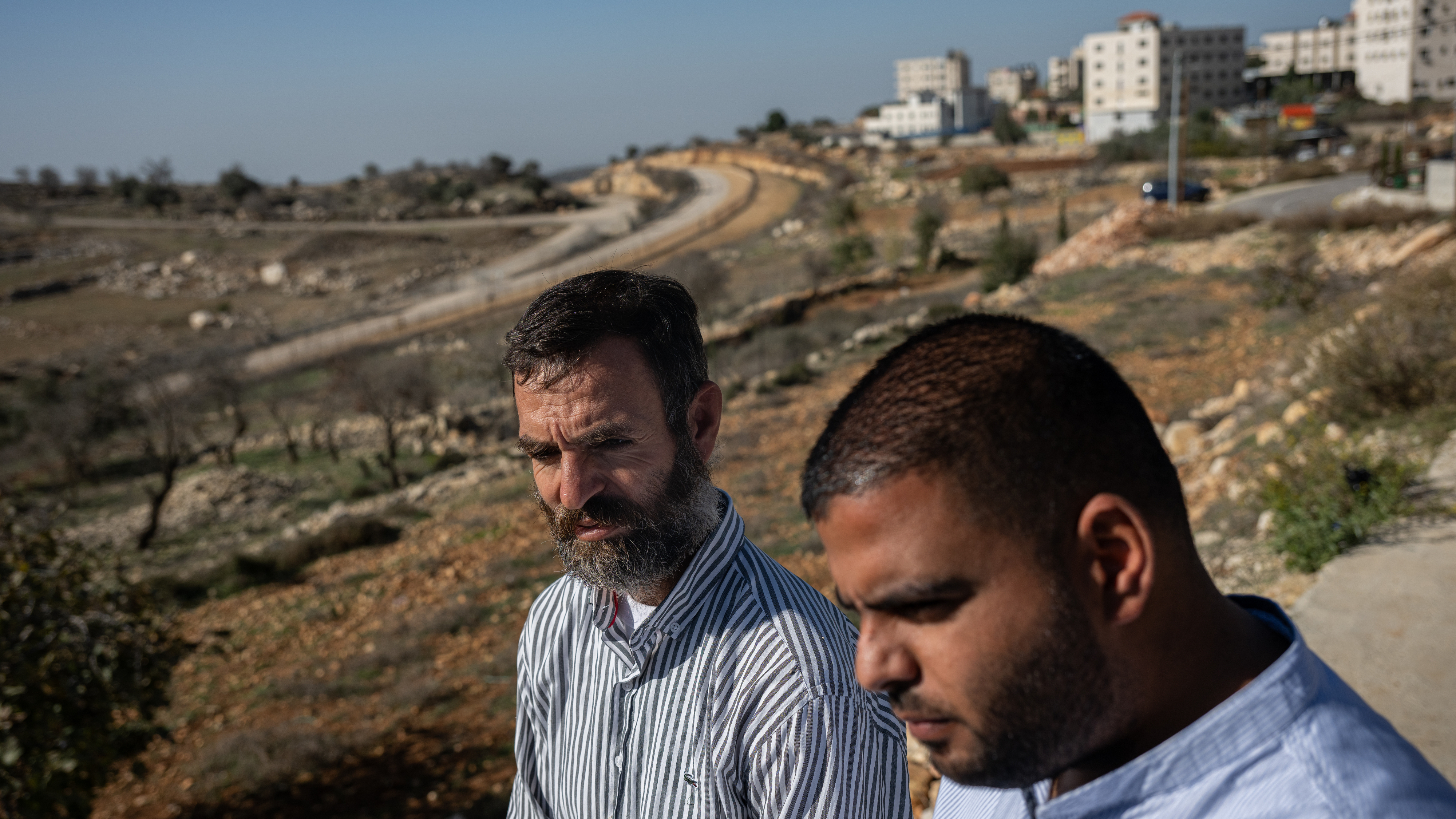 Palestinian farmers Naser El Khatib and Thaer El Taher stand on land filled with their olive trees at the edge of Beitunia, across from an area controlled by Israel in the occupied West Bank, on Dec. 2.
