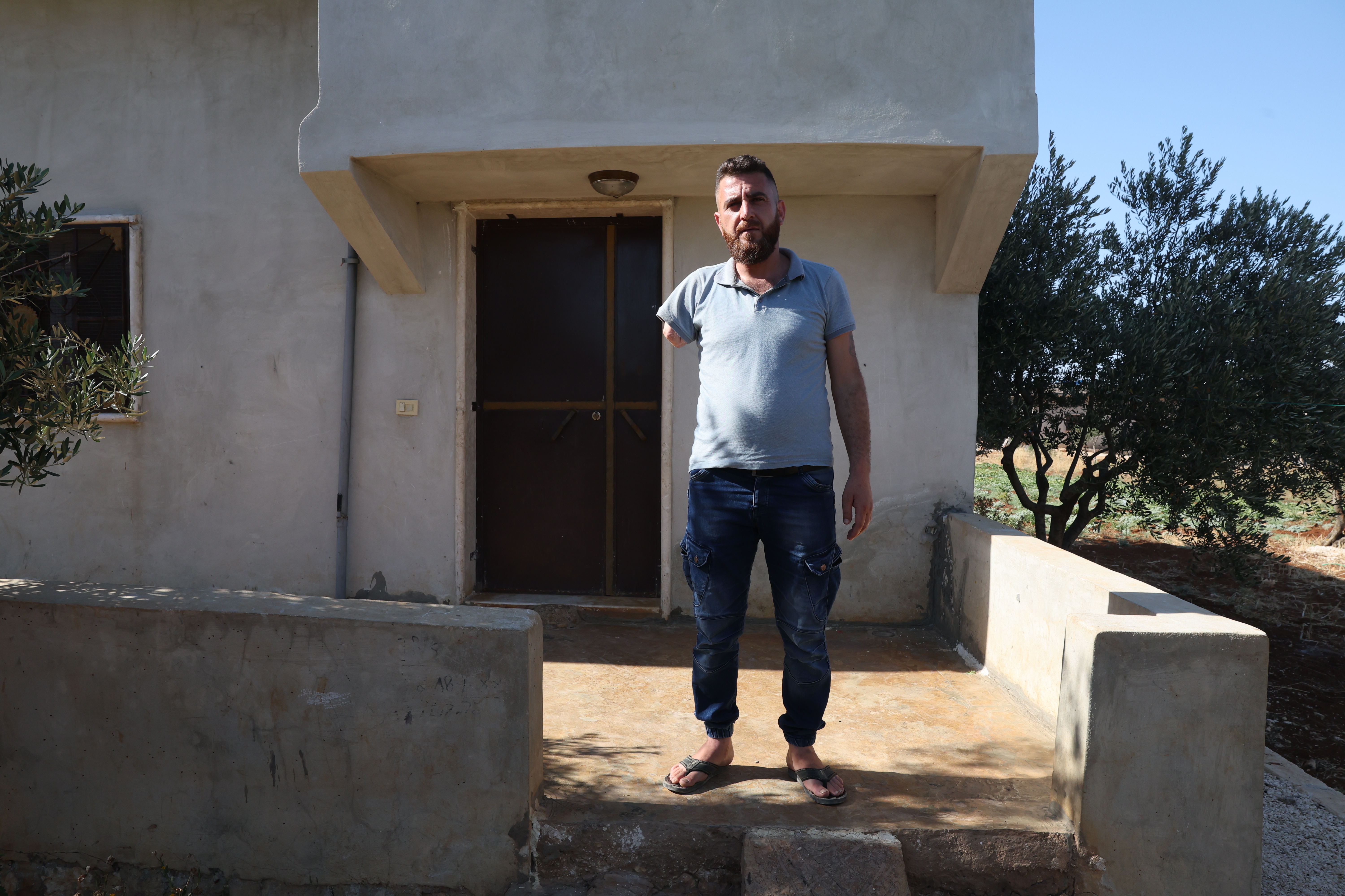 HATAN, SYRIA — Barakat Ahmad Barakat is pictured in front of his house in the village of Hatan in the West valley of Barisha, on June 24th. He explains where and how his arm was blown off and his two friends were killed by U.S. helicopter fire during the attack of the compound of ISIS leader Abu Bakr al-Baghdadi on October 2019. Click here for the full story.