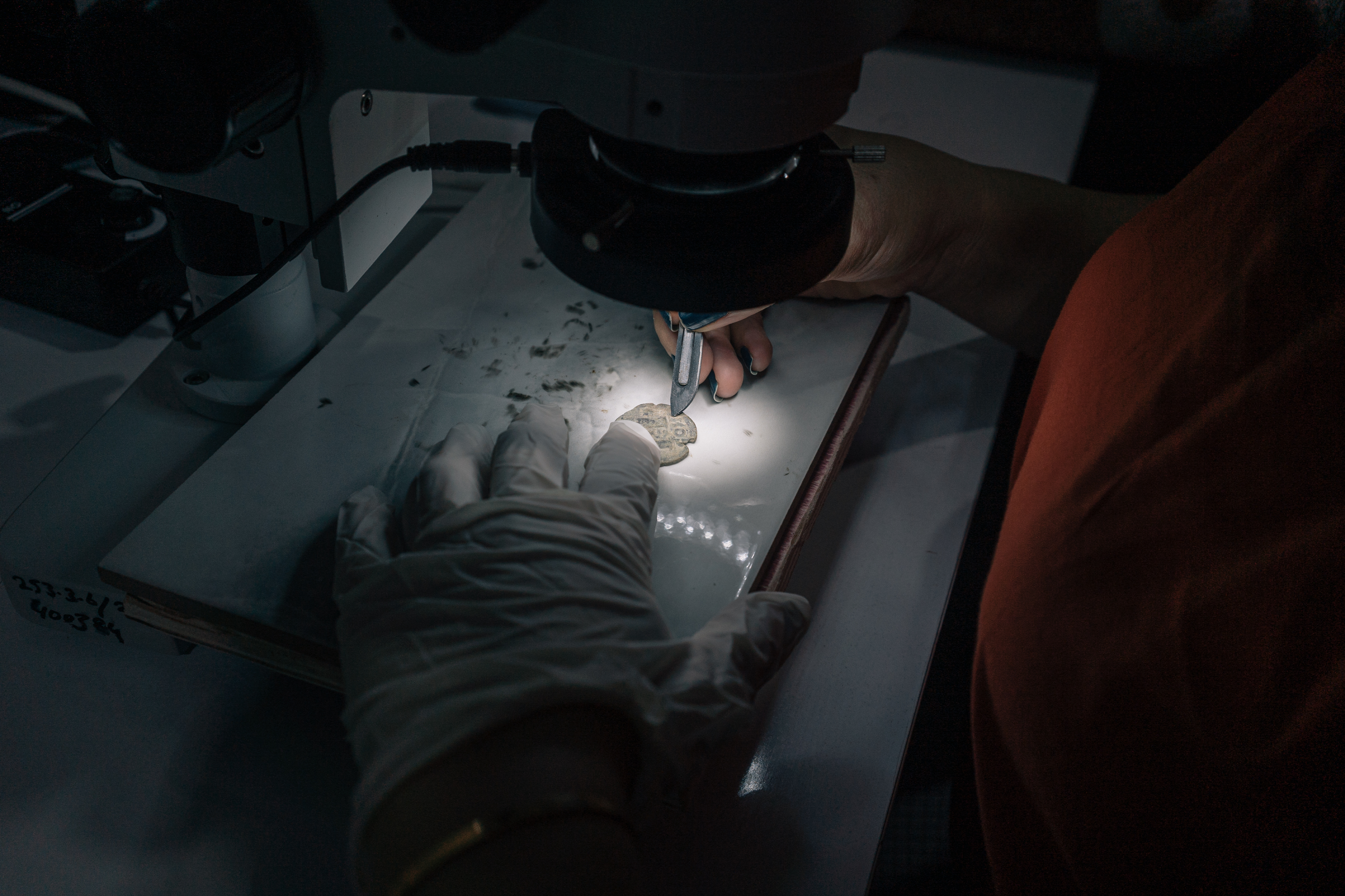 DIYARBAKIR PROVINCE, TURKEY — A member of the Zerzevan castle excavation and restoration team looks into a microscope while scraping a coin found at an archeological site. Click here for the full story.