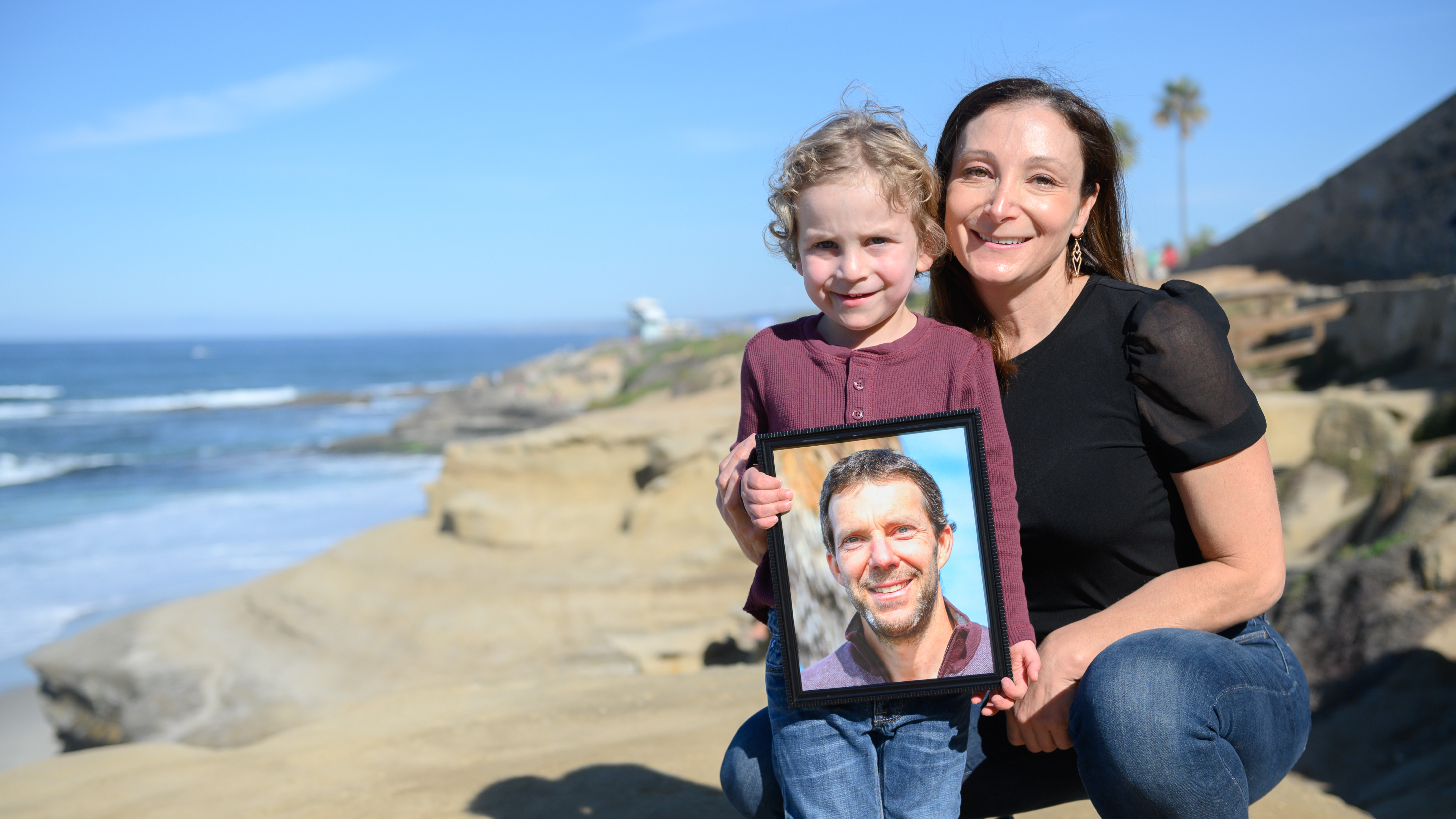 Laura Keenan and her son, Evan, hold a photo of her late husband Matt Keenan, who was killed while riding his bike in San Diego in 2021.