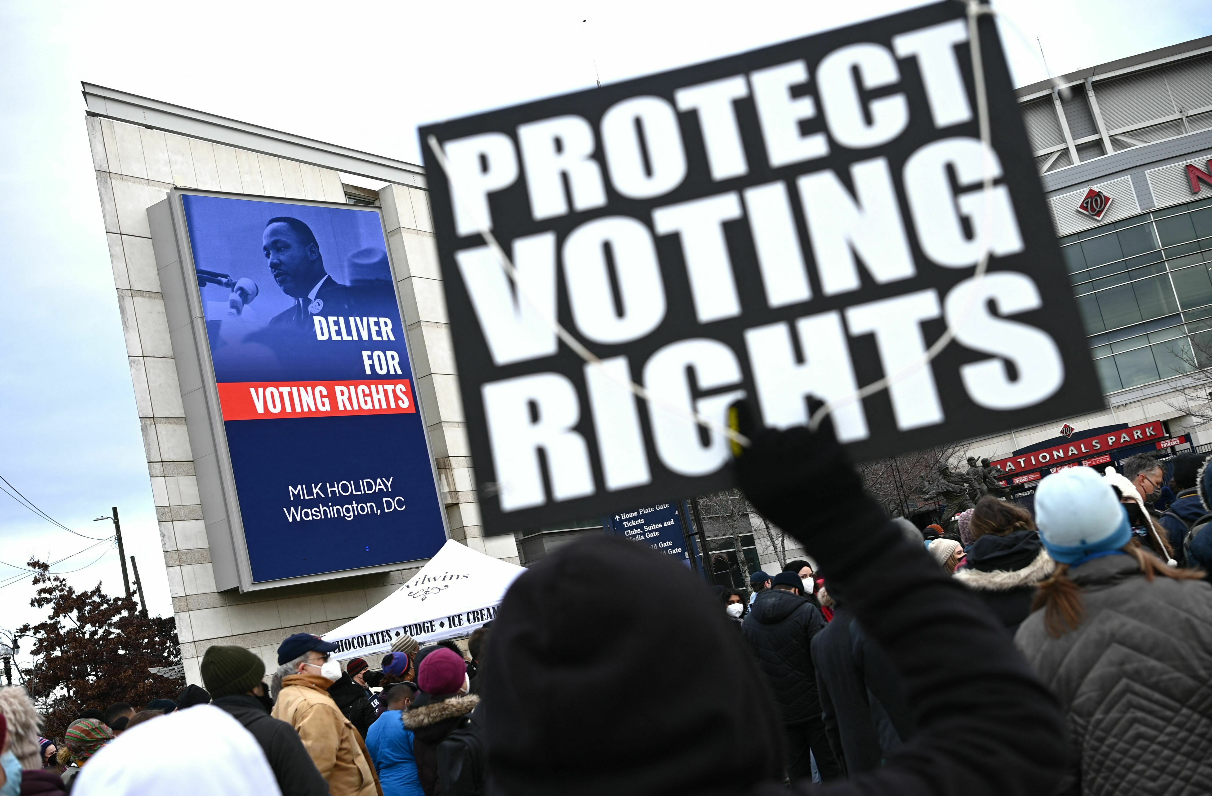 A participant in the annual Martin Luther King Jr. Memorial Peace Walk in Washington, D.C., holds a sign that says &quot;PROTECT VOTING RIGHTS&quot; in 2022. (AFP via Getty Images)