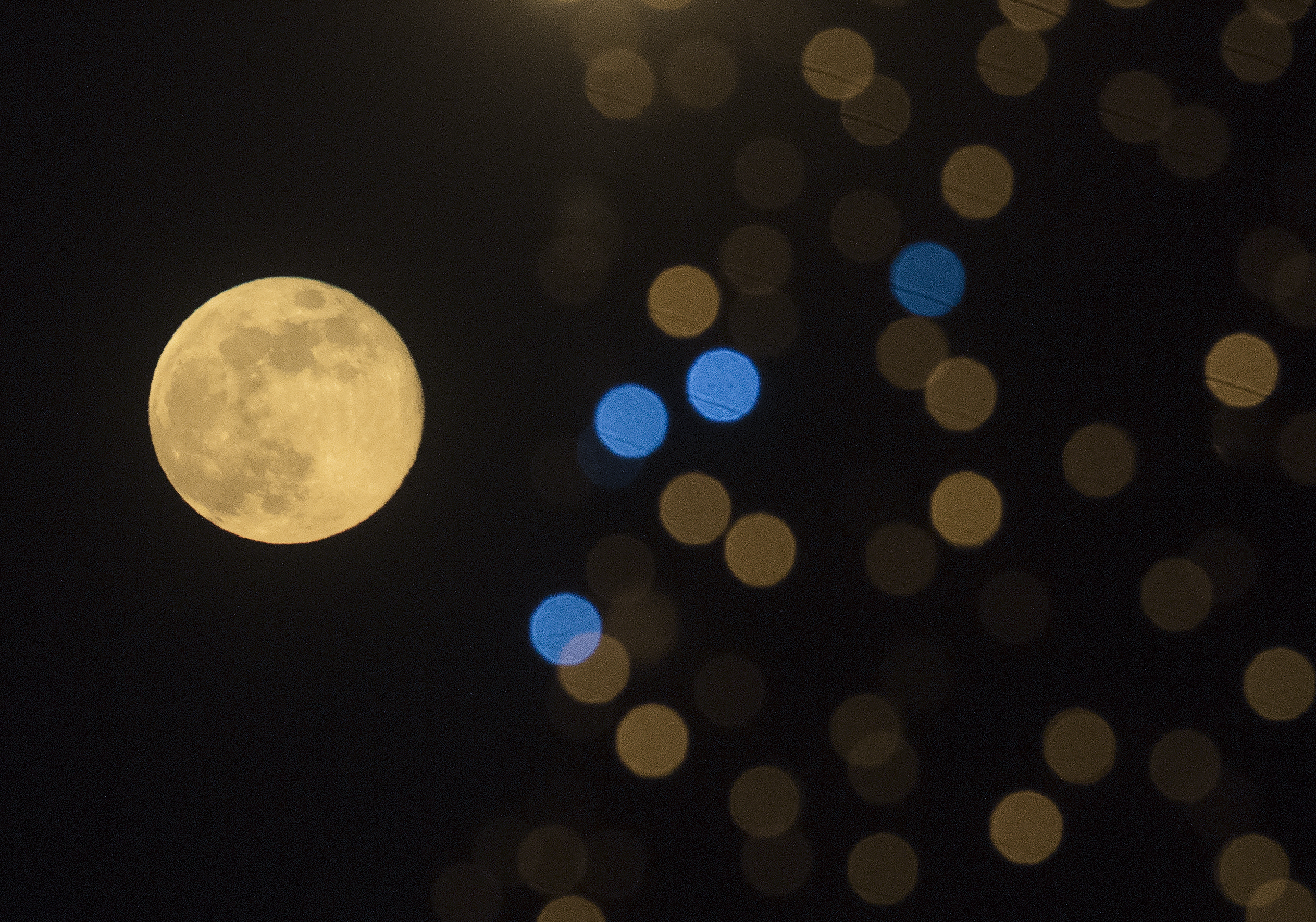 This photograph taken on December 27, 2023, shows the last full moon of the year, also known as the &quot;Cold Moon,&quot; behind New Year's decorations in Skopje, the capital of the Republic of Macedonia. (AFP via Getty Images)