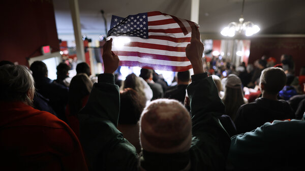 A woman holds up a small U.S. flag during a campaign rally by GOP presidential candidate and former President Donald Trump at the Rochester Opera House on Jan. 21 in Rochester, N.H.