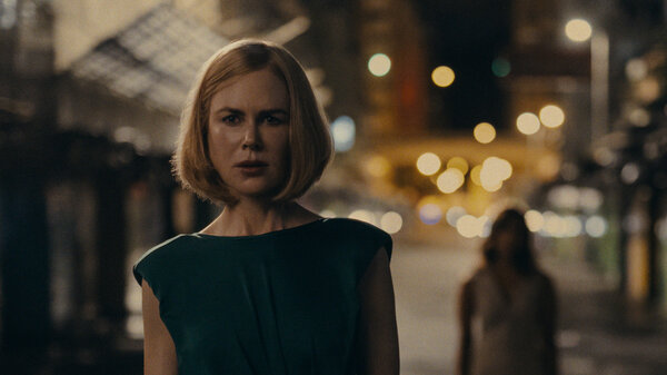 Nicole Kidman walks down a dark street, seemingly being followed by another figure.